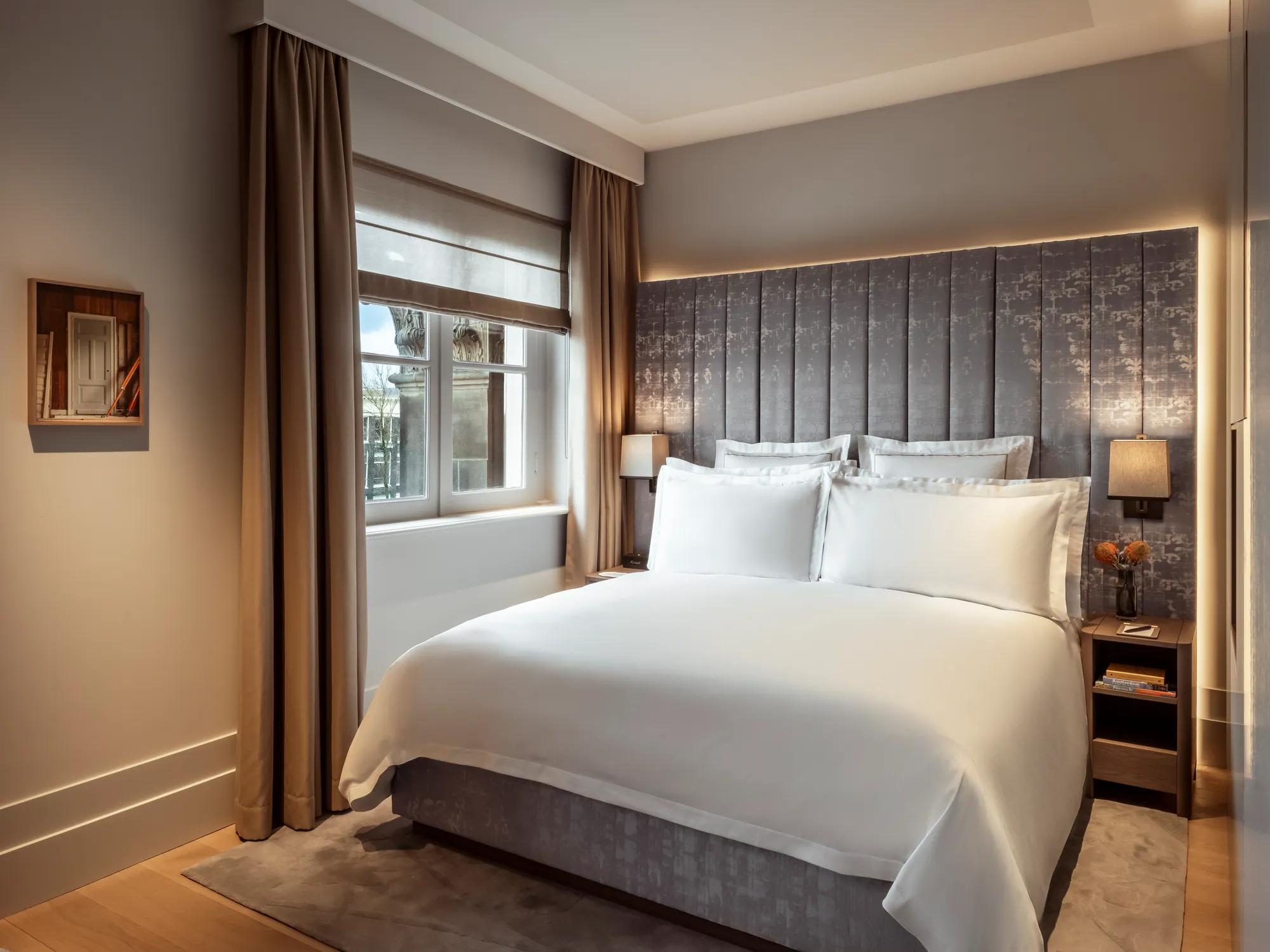 Rosewood Amsterdam: a Canal View Premier Room with a padded headboard and a window over the canal