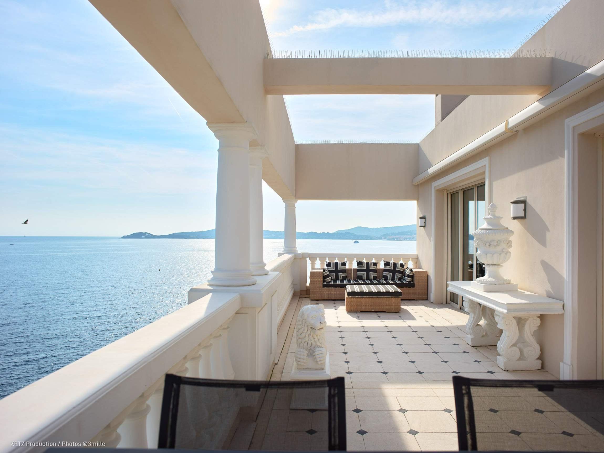 A modernist terrace with white columns overlooks calm Mediterranean waters