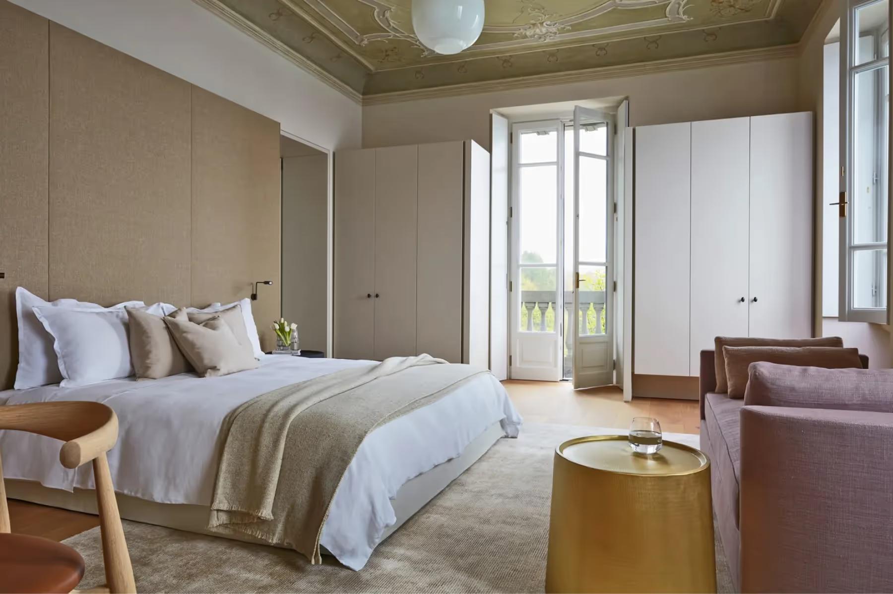 Villa Patrizia: a bright bedroom with beamed ceiling, French doors to a balcony, and lake views