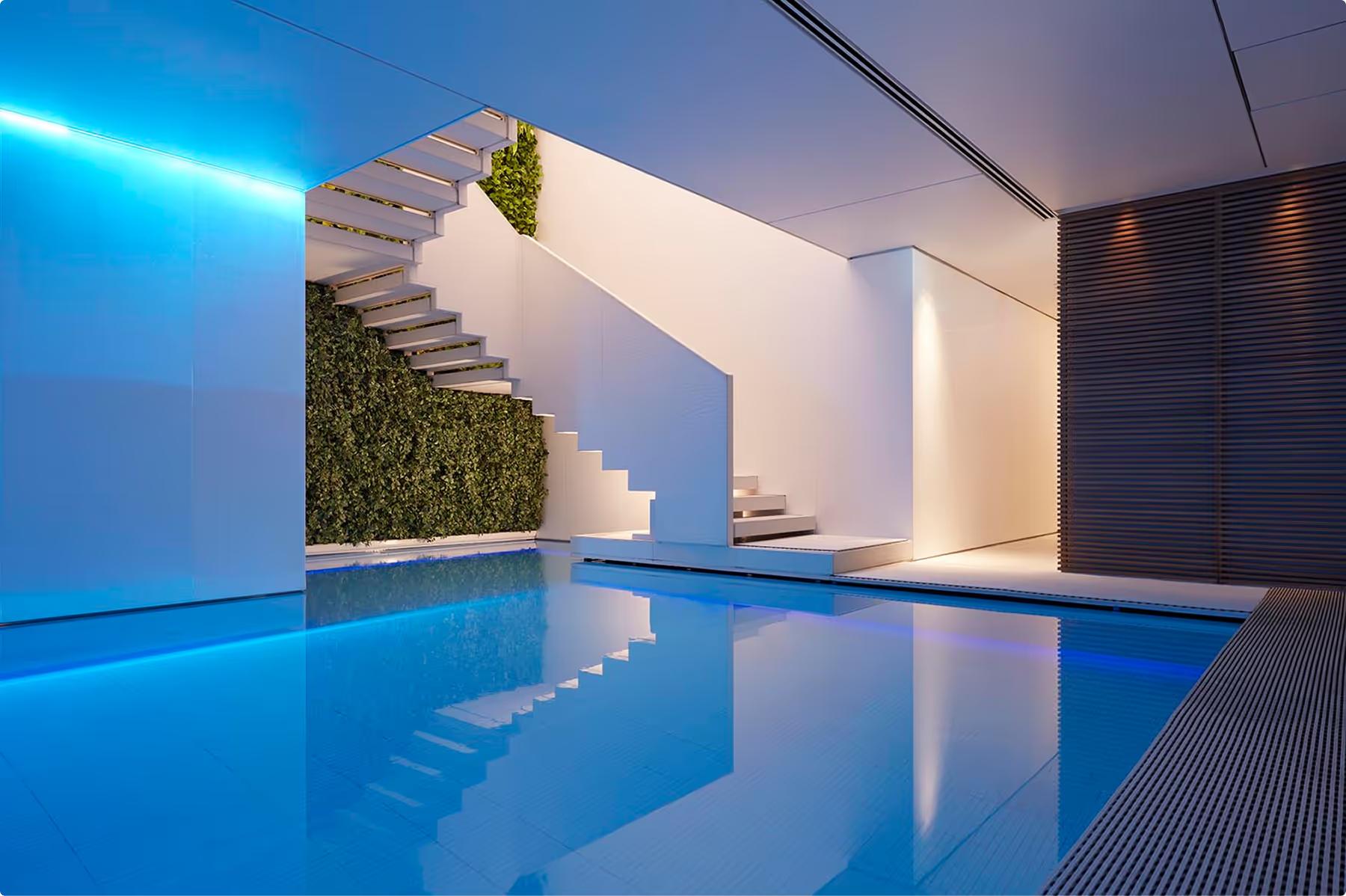 Illuminated swimming pool with blue water, modern white columns, and spa area