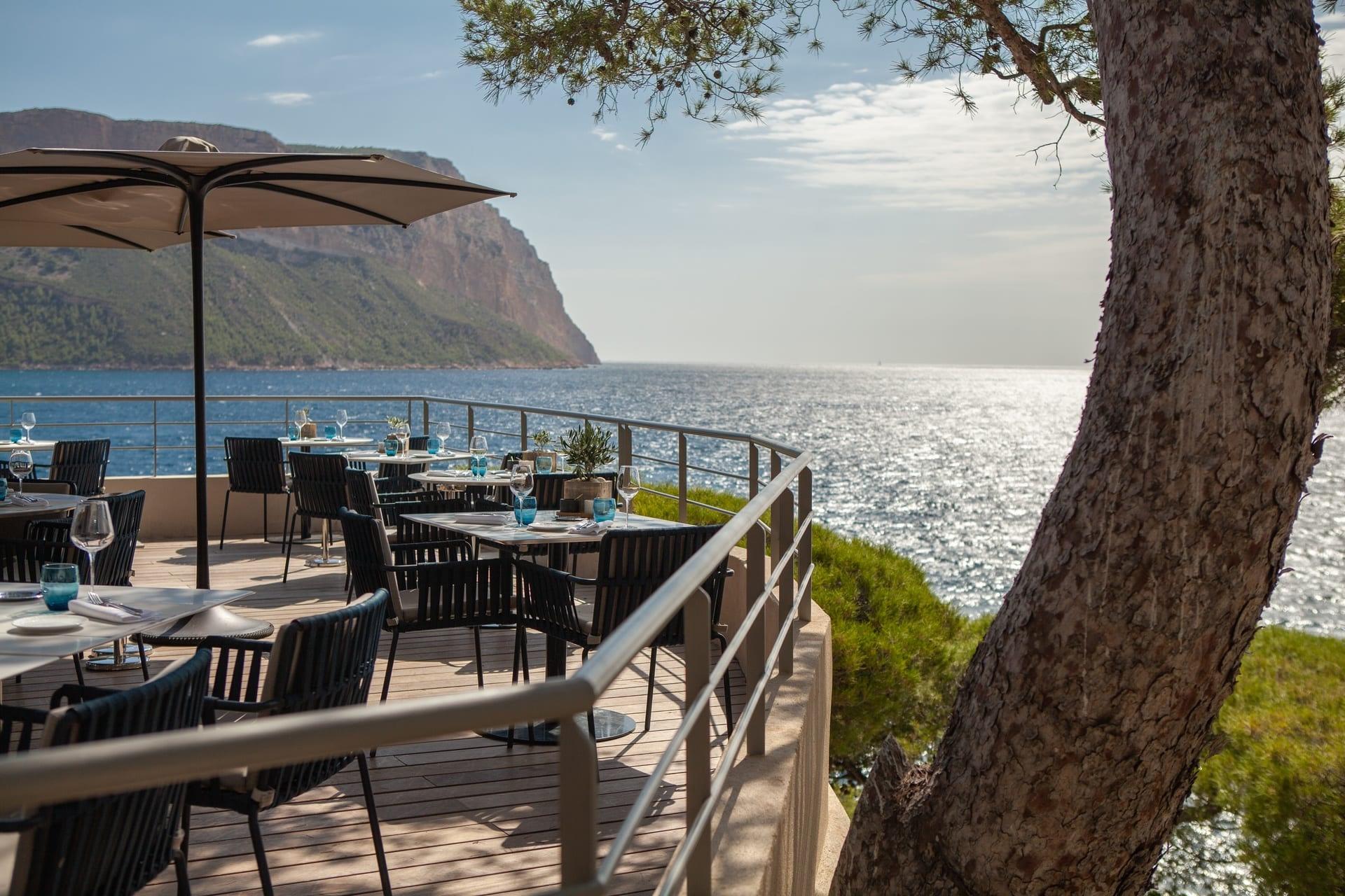 Les Roches Blanches: a seaside dining terrace with shaded seating area and Mediterranean views at the property