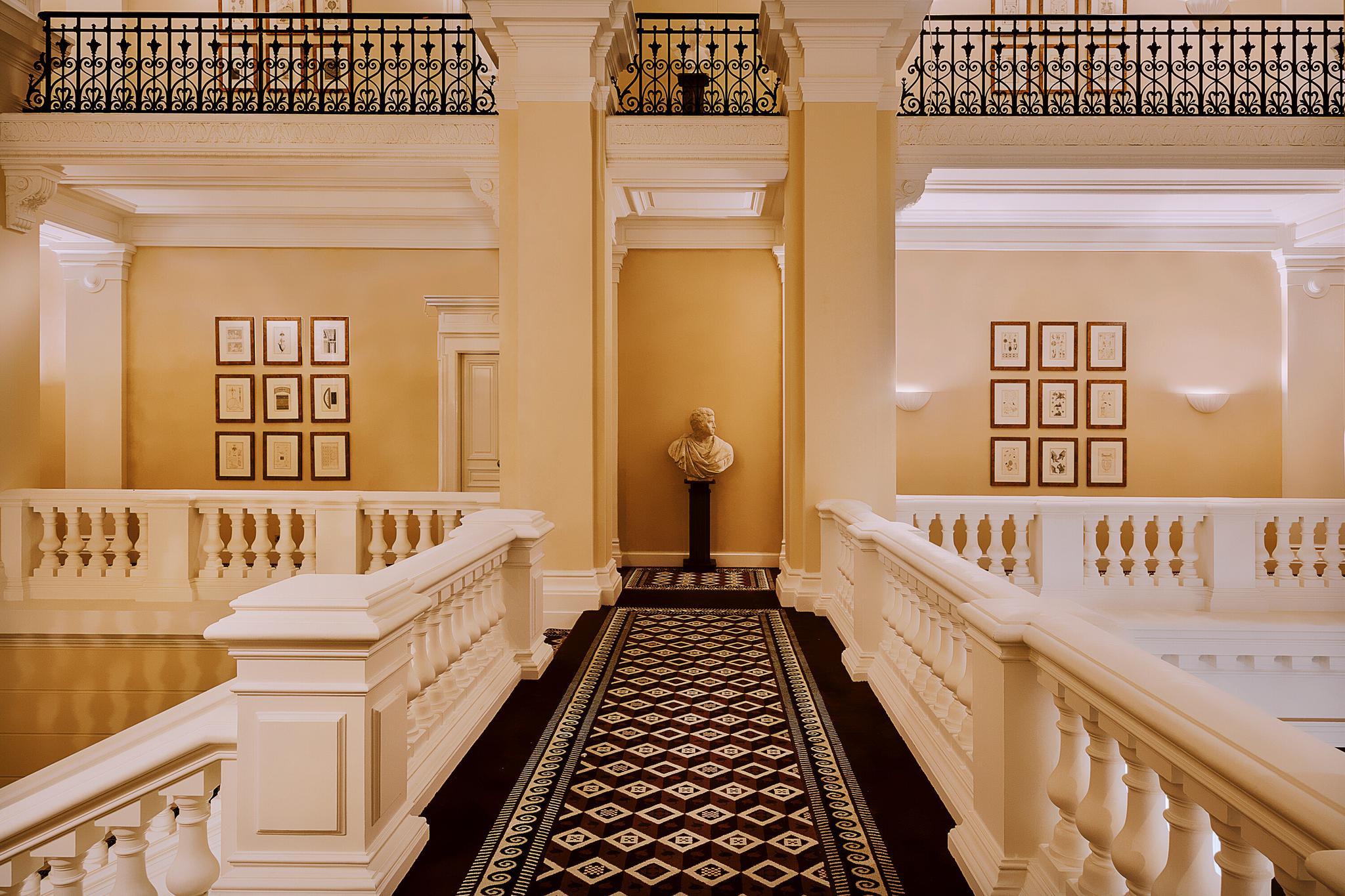 Saint James: grand lobby with wood paneling, potted palms, and cream-colored furnishings