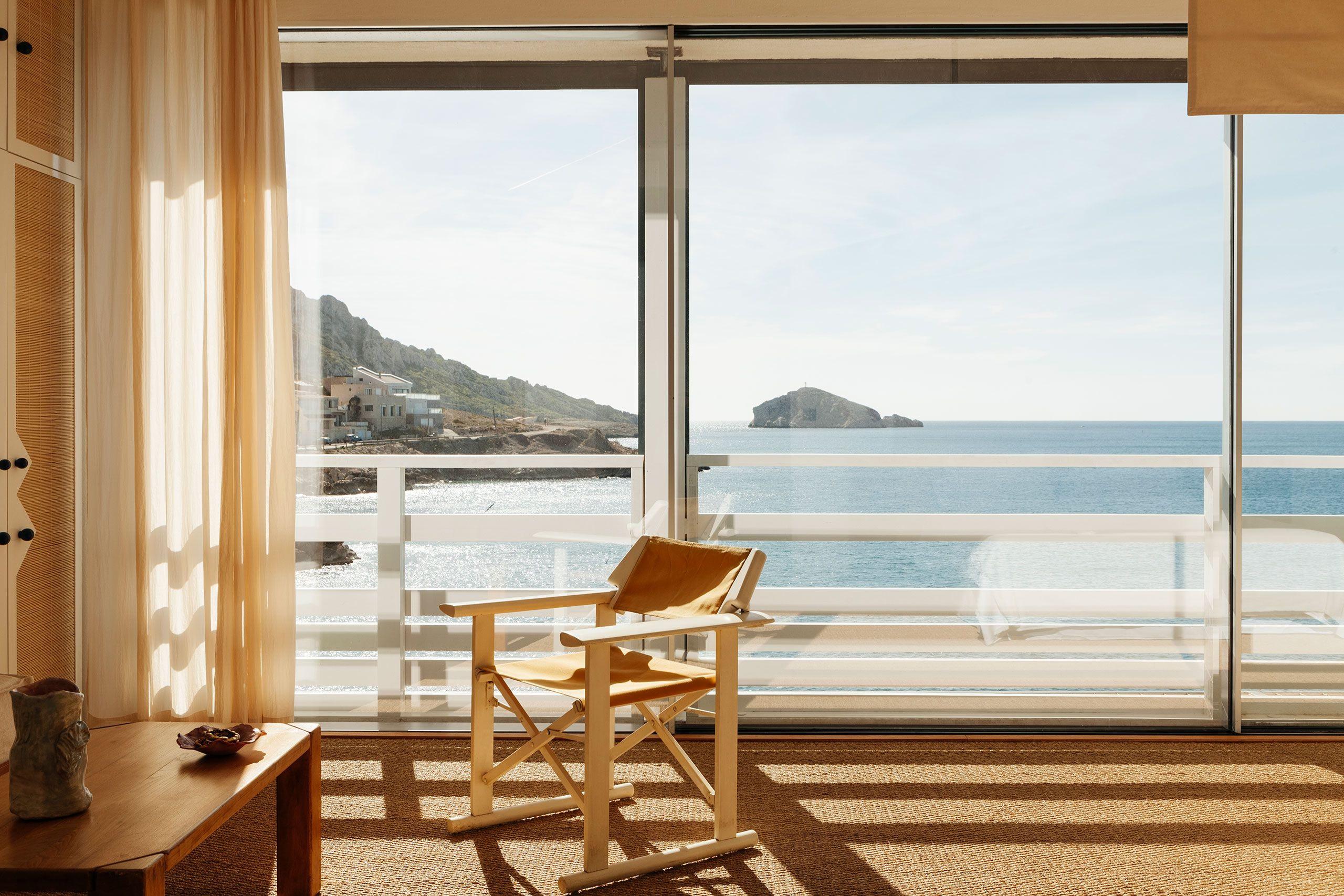 A cabanon room at Tuba Club in Les Goudes, with a canvas chair facing the sea through open glass