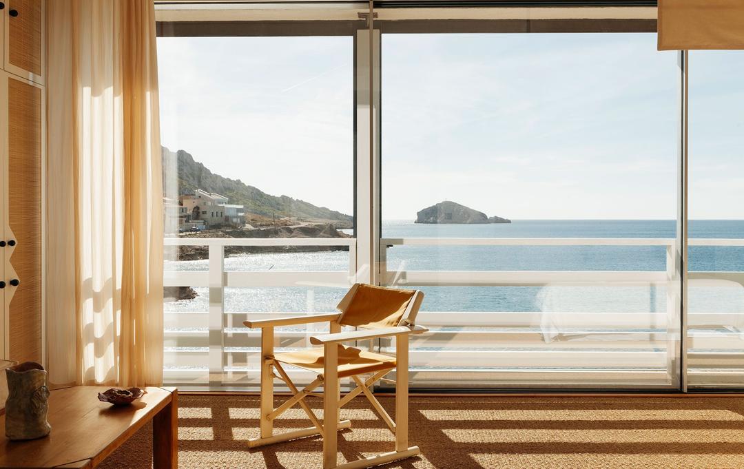 A cabanon at Tuba Club, a canvas chair facing the sea through open glass