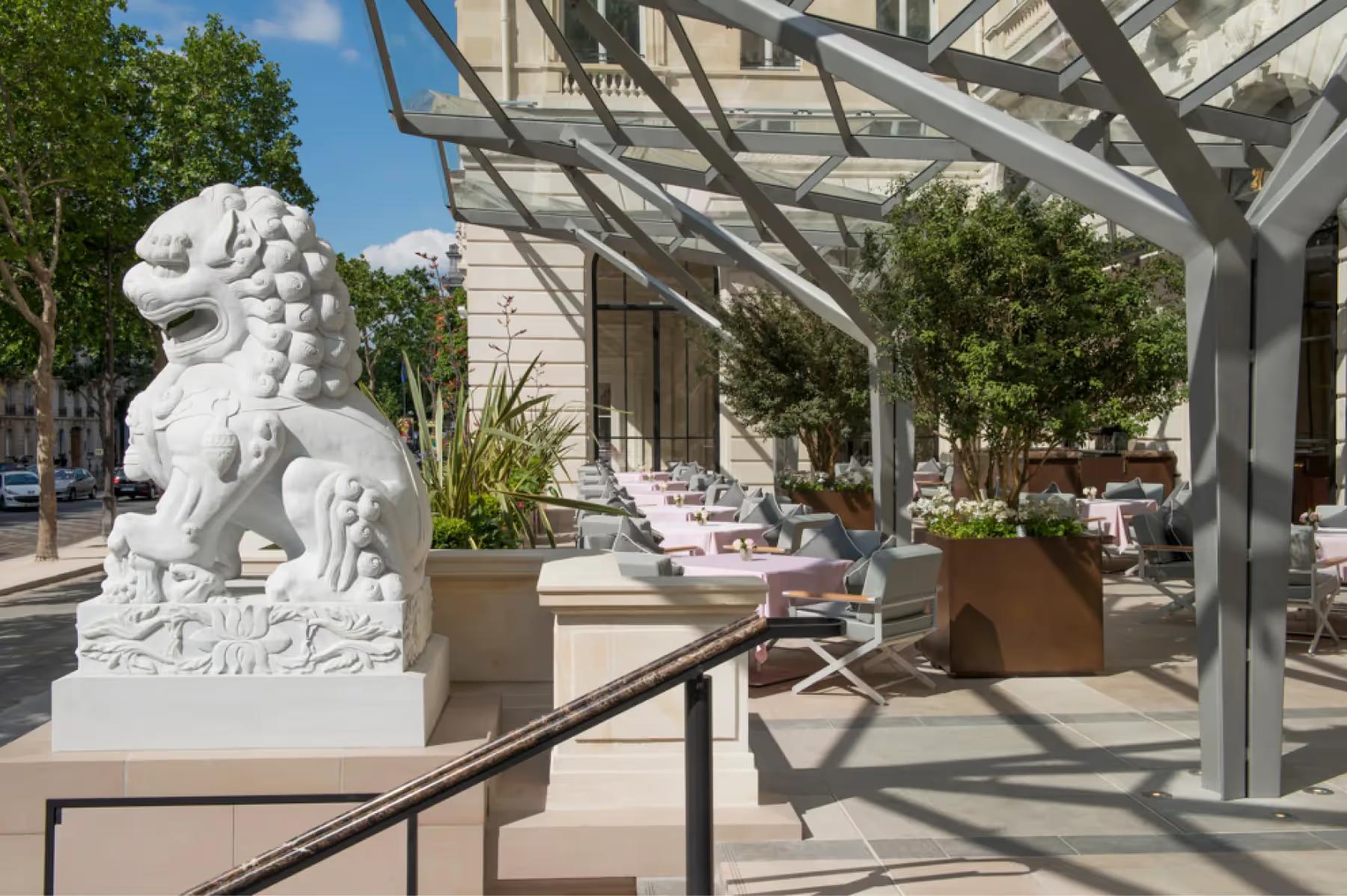 The Peninsula: dining terrace under pergola with pink flowers, green vines, and dressed tables in daylight