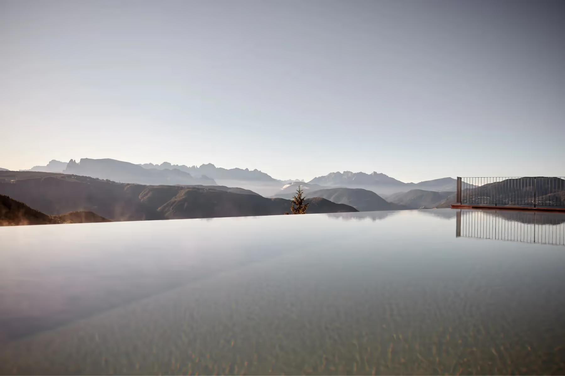 Infinity pool reflecting mountains at dawn in misty atmospheric light