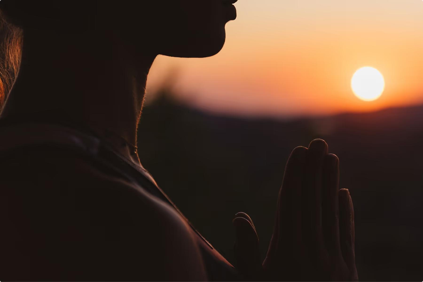 Person in meditation pose at dusk with mountain backdrop