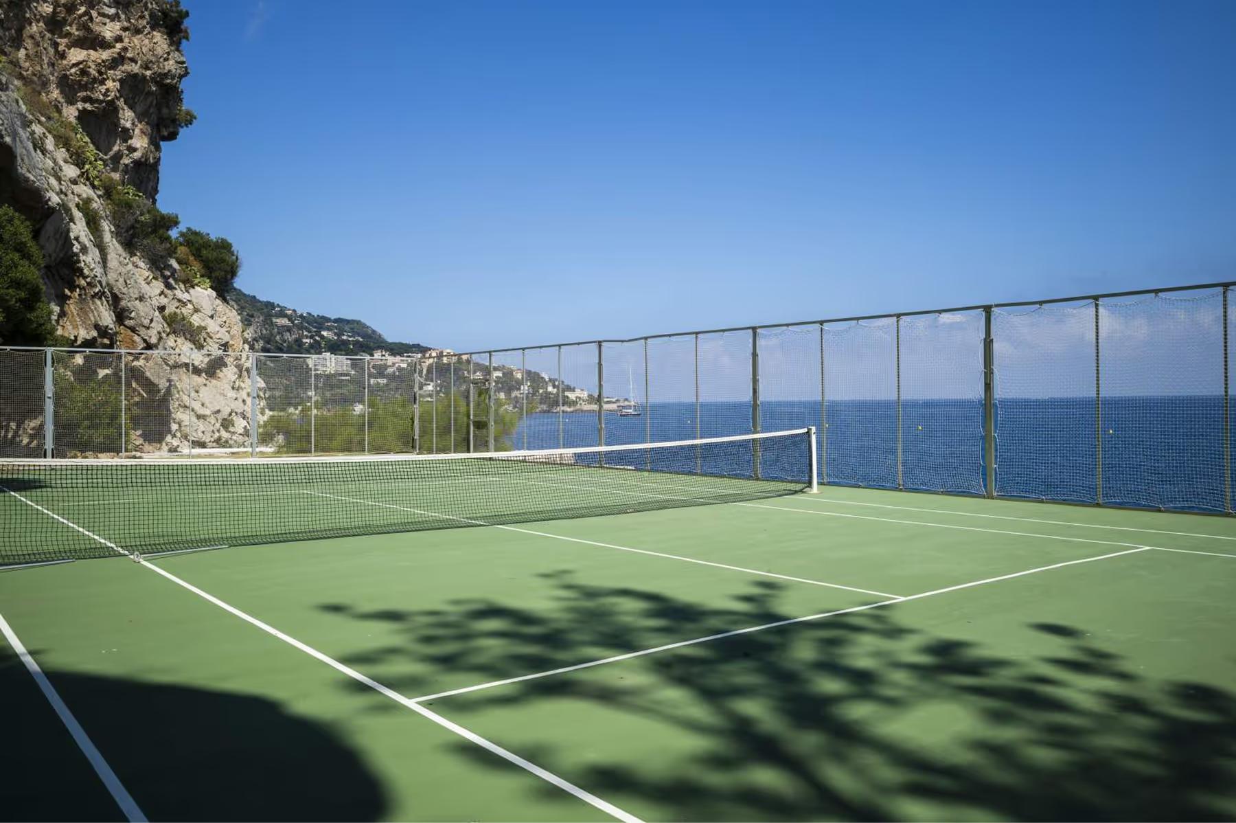 Hotel Cap-Estel: a tennis court with bright green surface and nets overlooking the sea