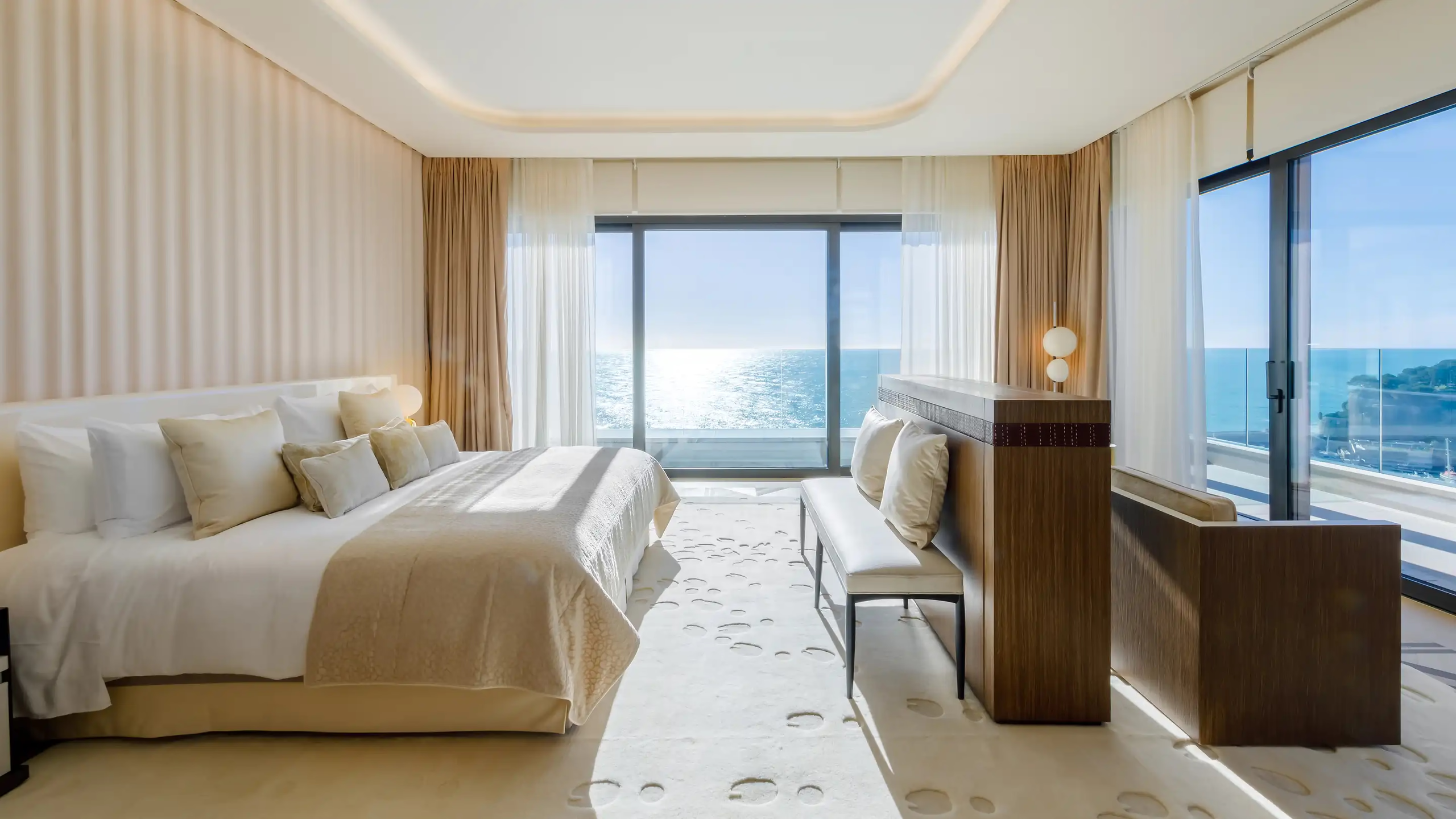 Hôtel de Paris Monte-Carlo: bedroom with white bedding, beige striped walls, open doors to sea view balcony