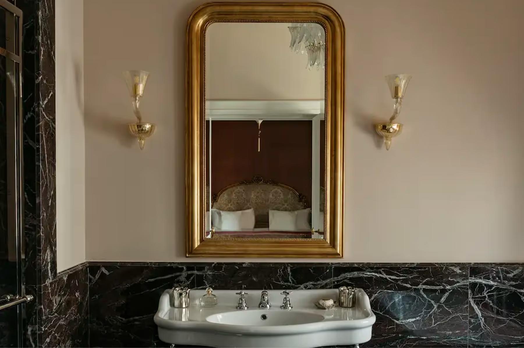 Passalacqua: an ornate gold-framed mirror above a marble sink with slate wall panels