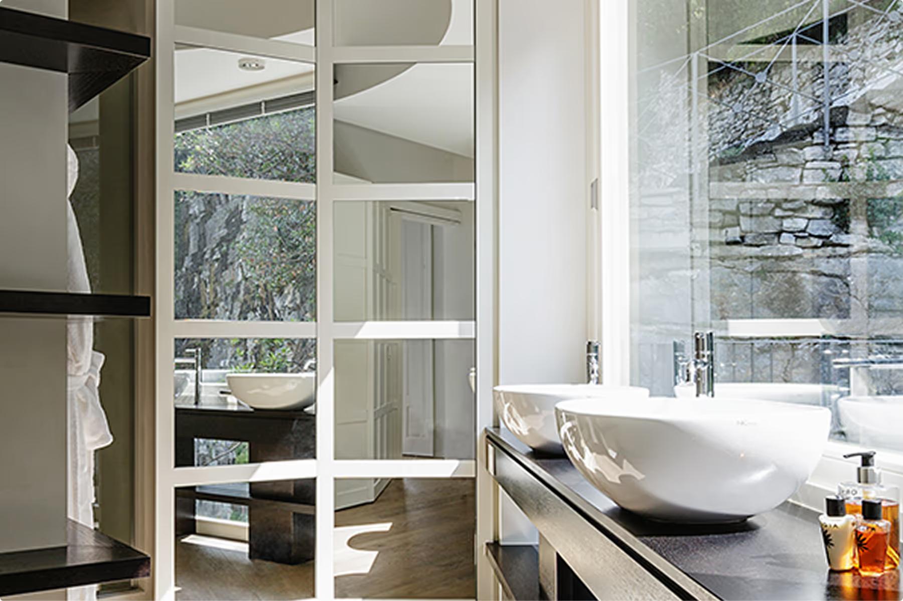 Villa Làrio: bathroom with marble surfaces, lit mirror vanity, and minimalist fixtures