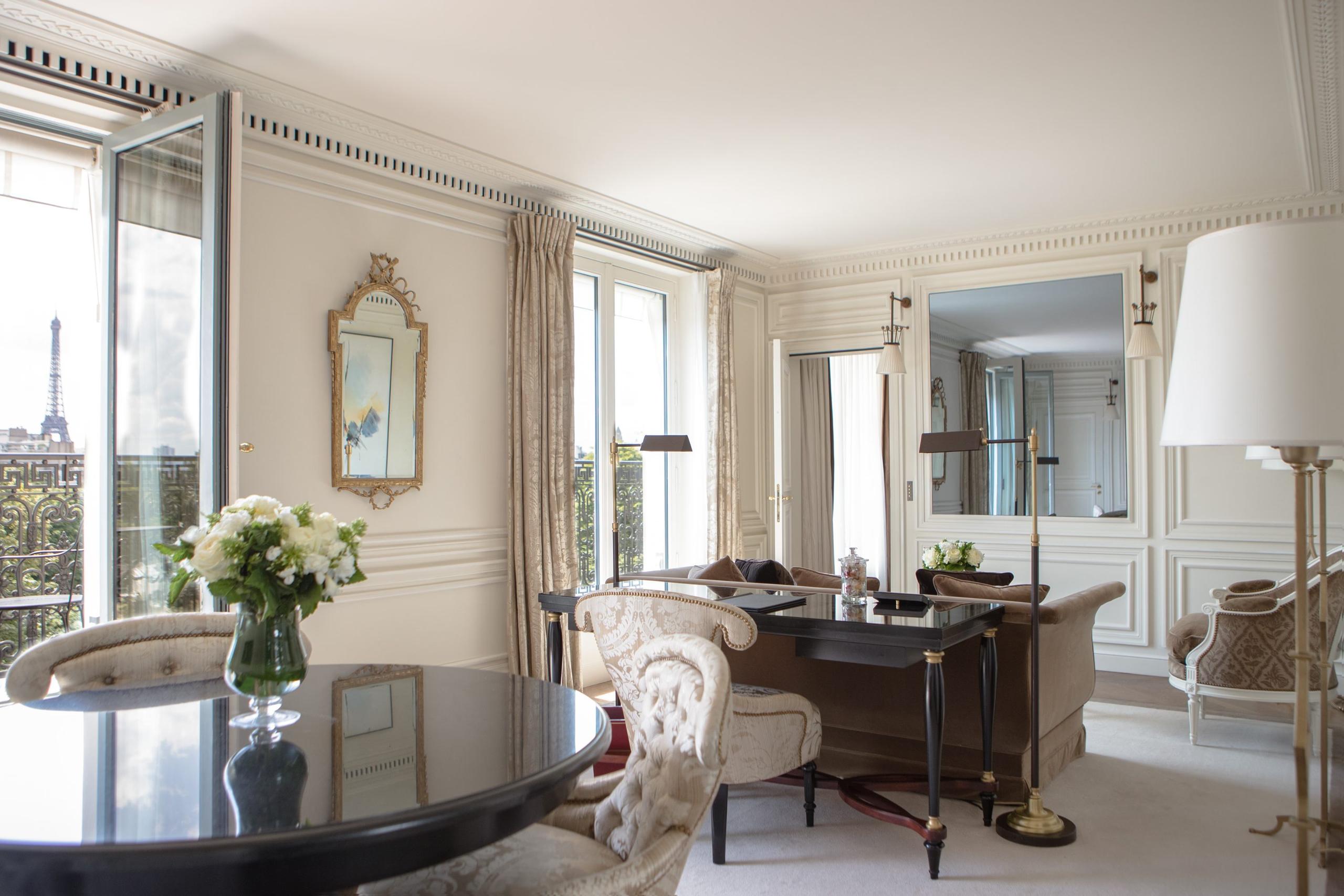 A sitting area with a writing desk, botanical accents, and floor-to-ceiling windows