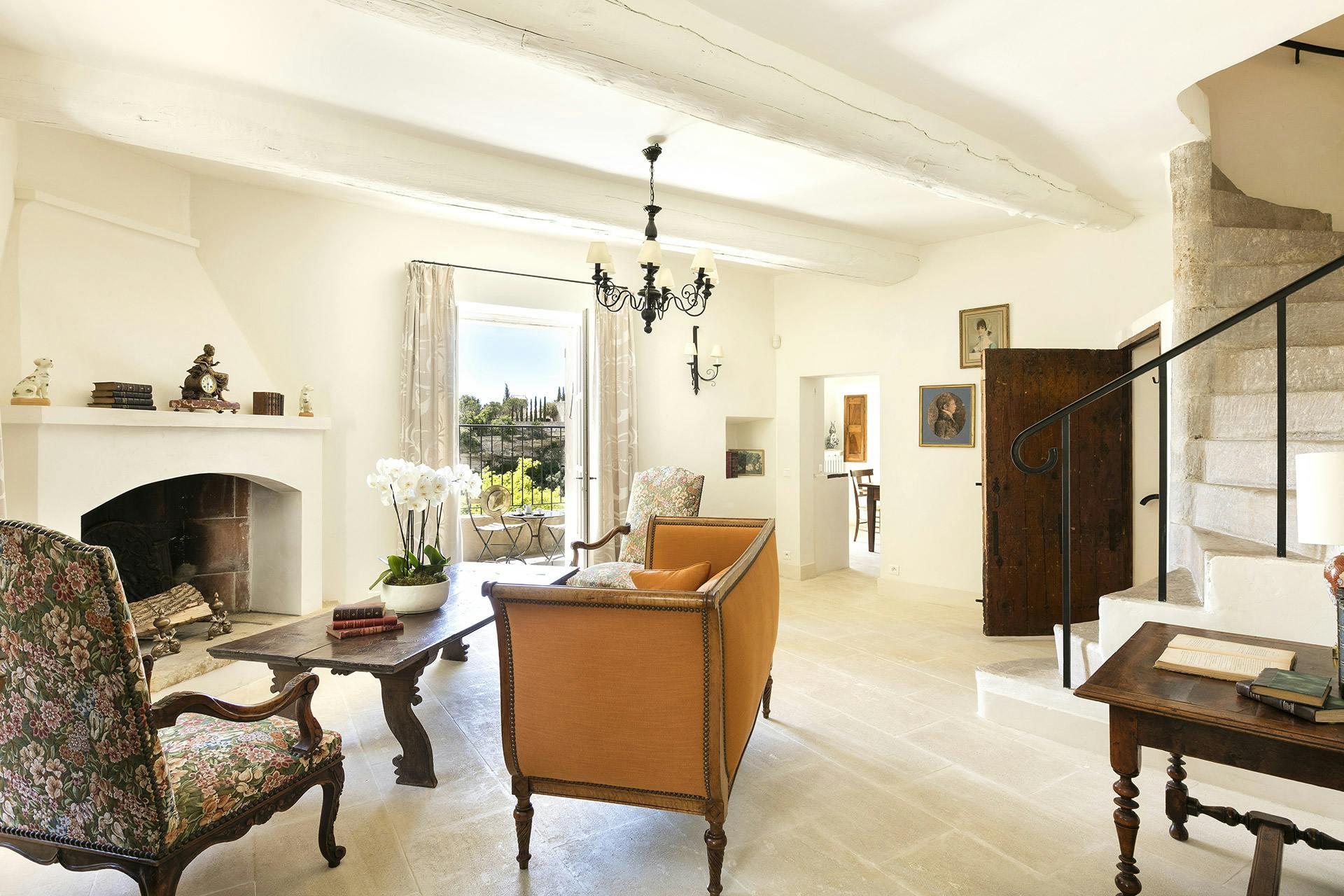 Airelles Gordes, La Bastide: suite with pale walls, chandelier, dining table, and garden view