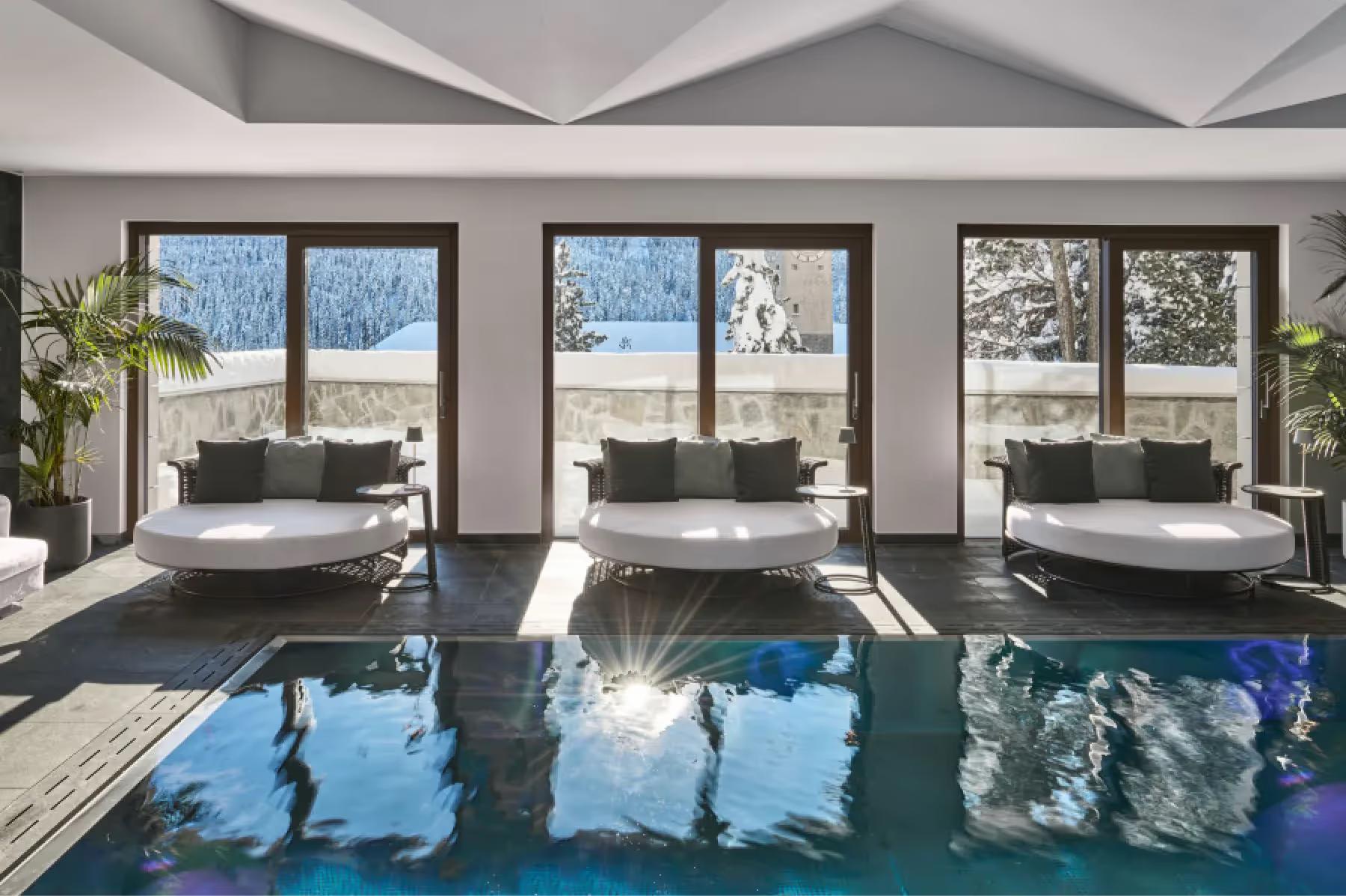 Grace La Margna St. Moritz: indoor pool with blue water, large windows, loungers, and alpine landscape beyond