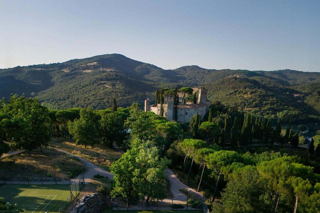 A grass tennis court below the castle at Reschio, hedged with cypresses