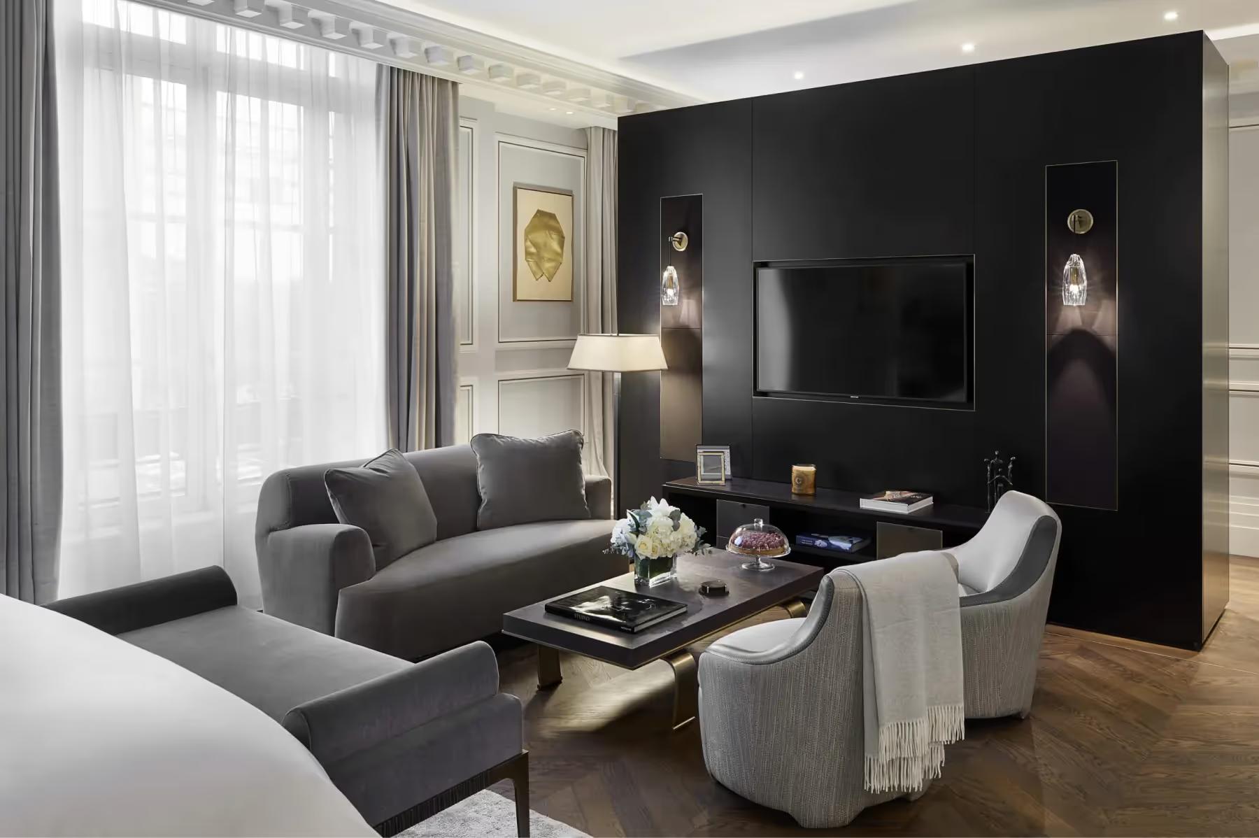 A living room with dark sofa, cream armchair, television, and black accent wall