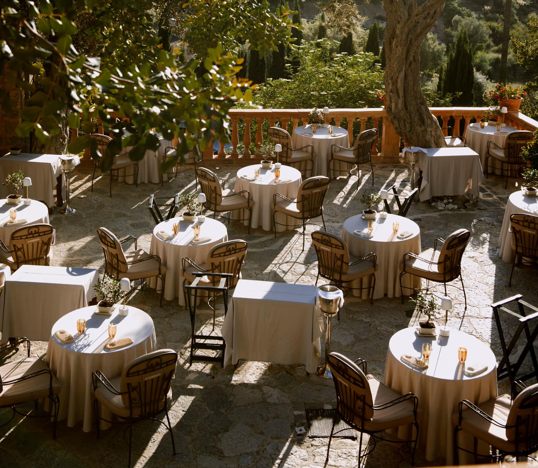 Tables with white tablecloths on a sunlit stone terrace at La Residencia in Mallorca
