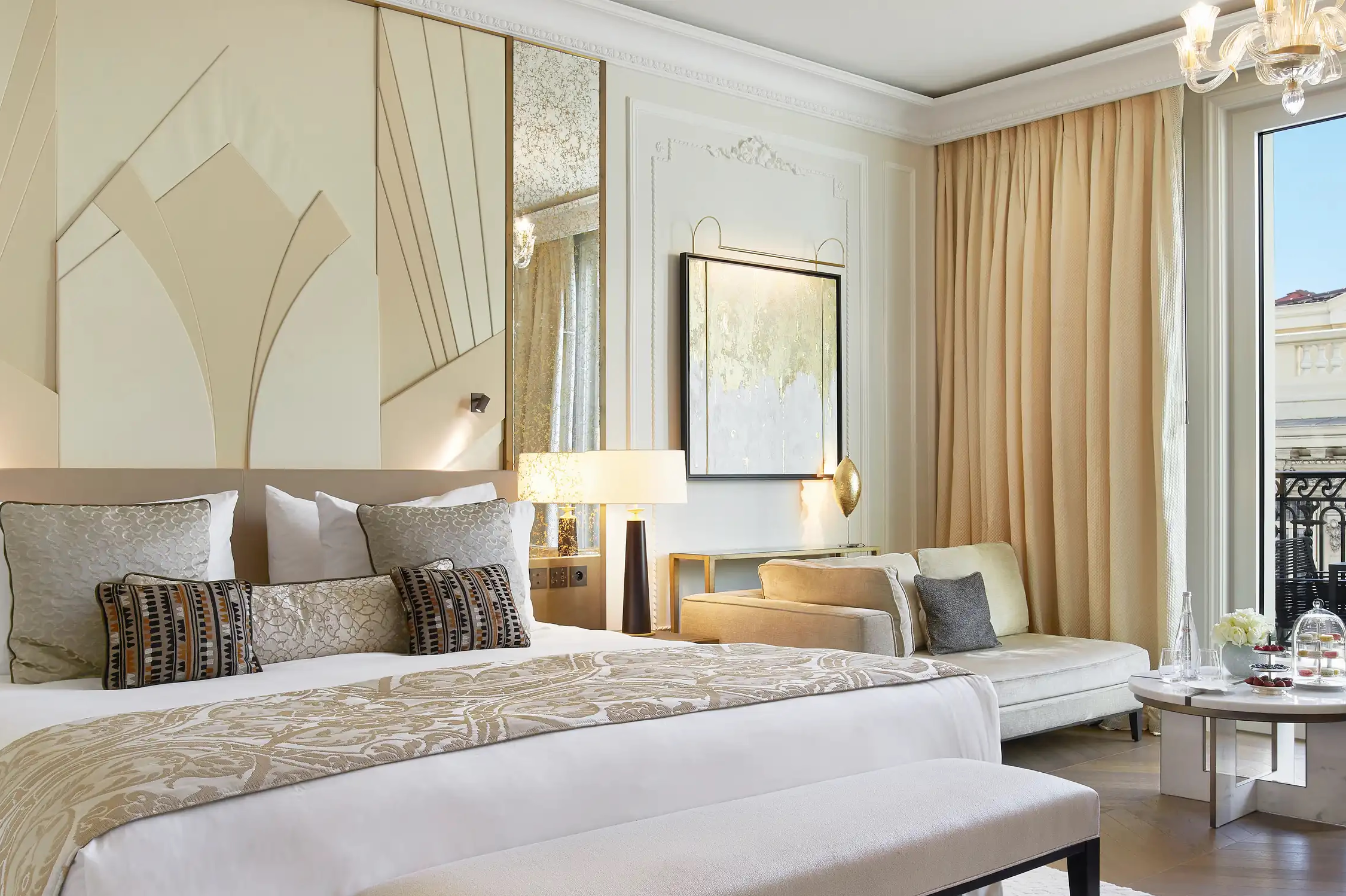 Bedroom with layered neutral bedding and open balcony door to sea view