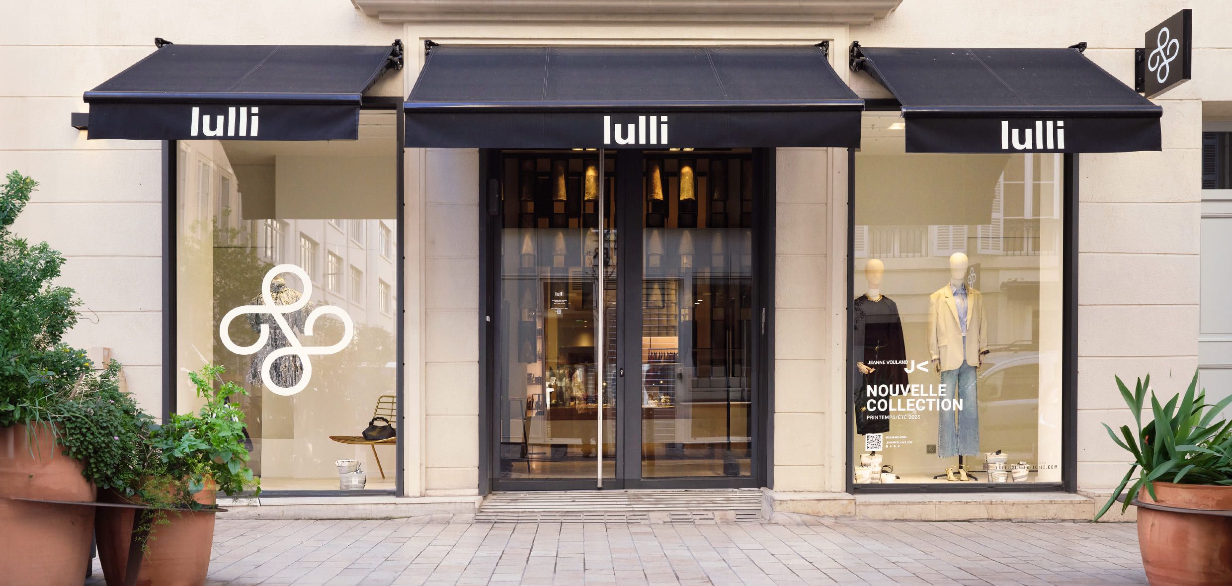 The black-awninged storefront of Lulli on Rue Paradis in Marseille, with clothing in the windows