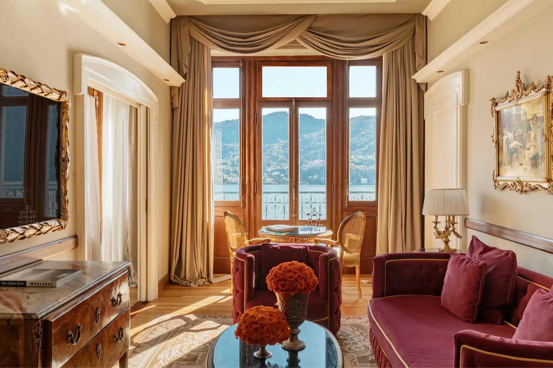 Grand Hotel Tremezzo: room with tall windows, burgundy armchair, and furniture positioned toward lake view
