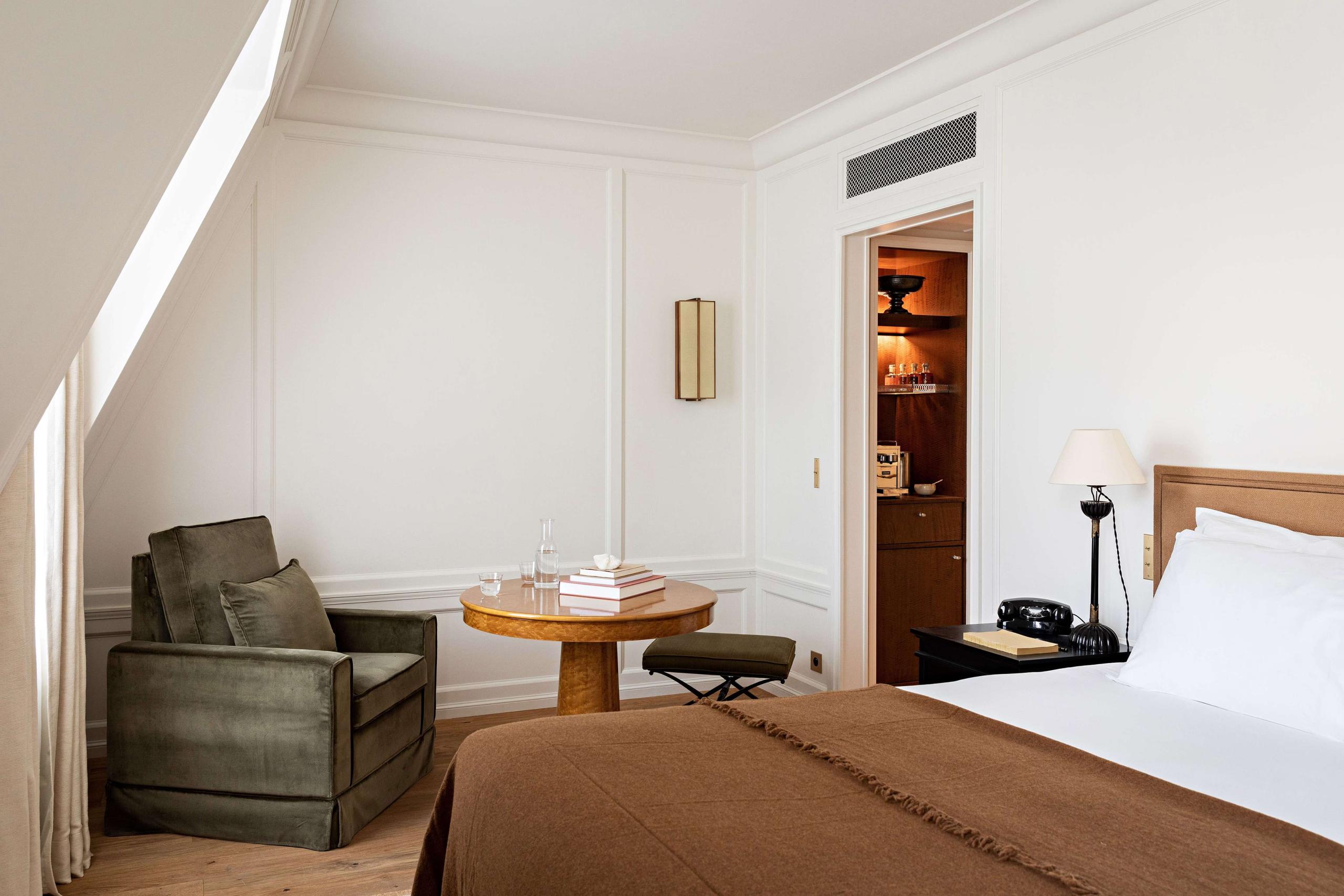 Hôtel Balzac: a bedroom with pale walls, sloped ceiling, simple wood furniture, and natural light