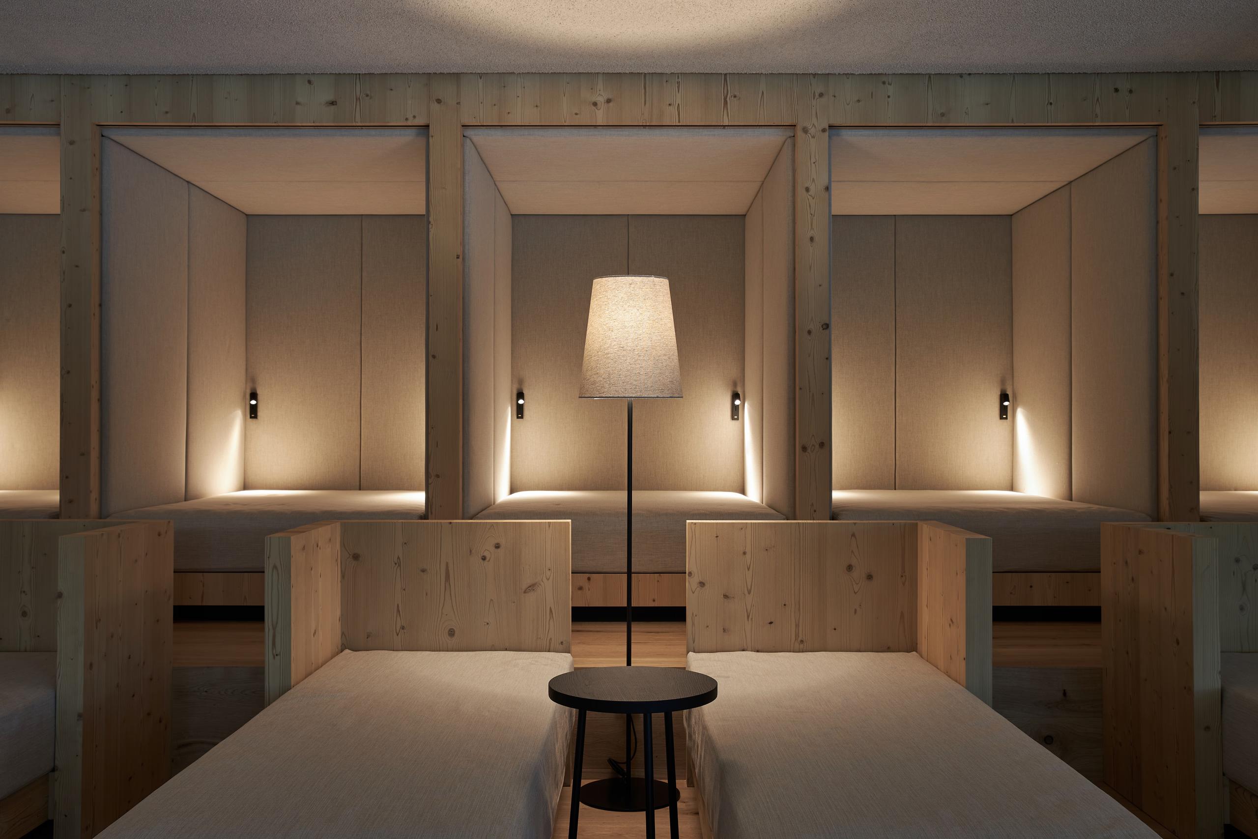 Forestis: a spa treatment room with a treatment table, wood cabinetry, and soft overhead and side lighting