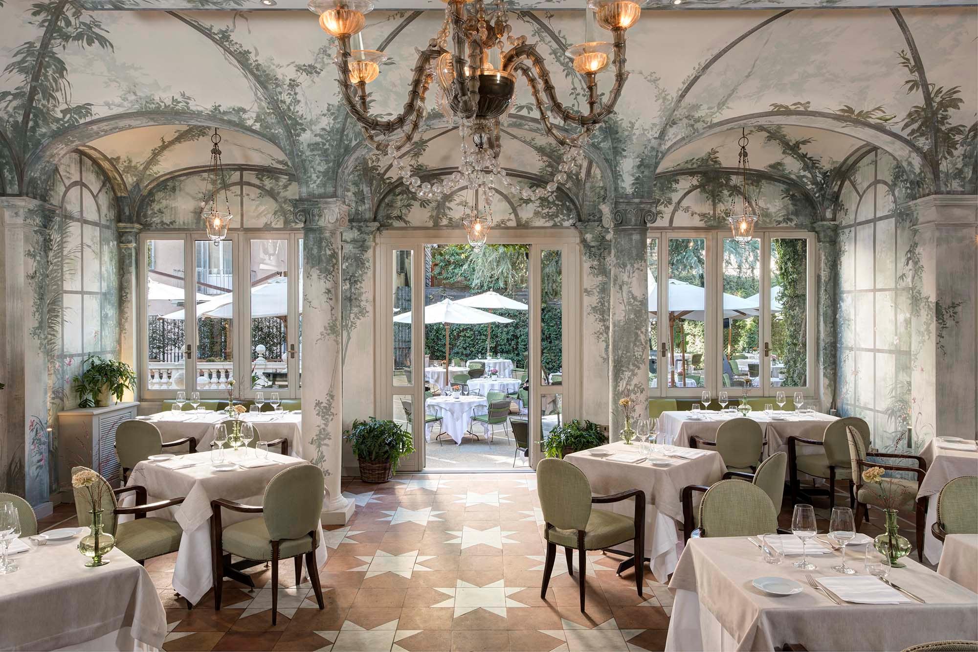 Elegant dining gallery with arched niches, columns, and fireplace beyond