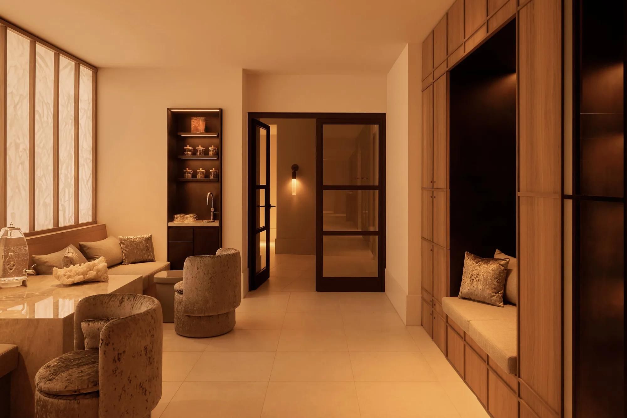 Rosewood Amsterdam: the Asaya spa lounge with upholstered armchairs, a cushioned bench, and shelving