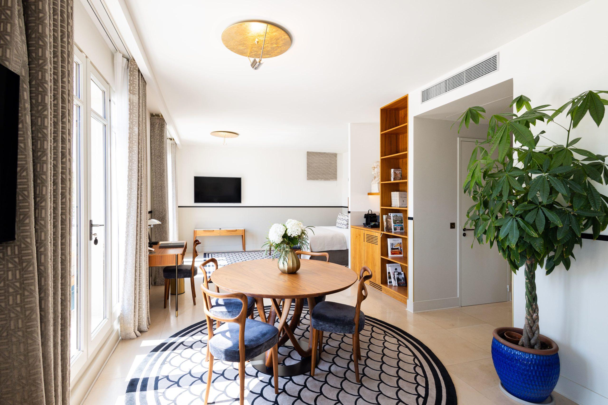 Les Roches Blanches: a suite with wooden furnishings, geometric rug, and living area with dining space visible