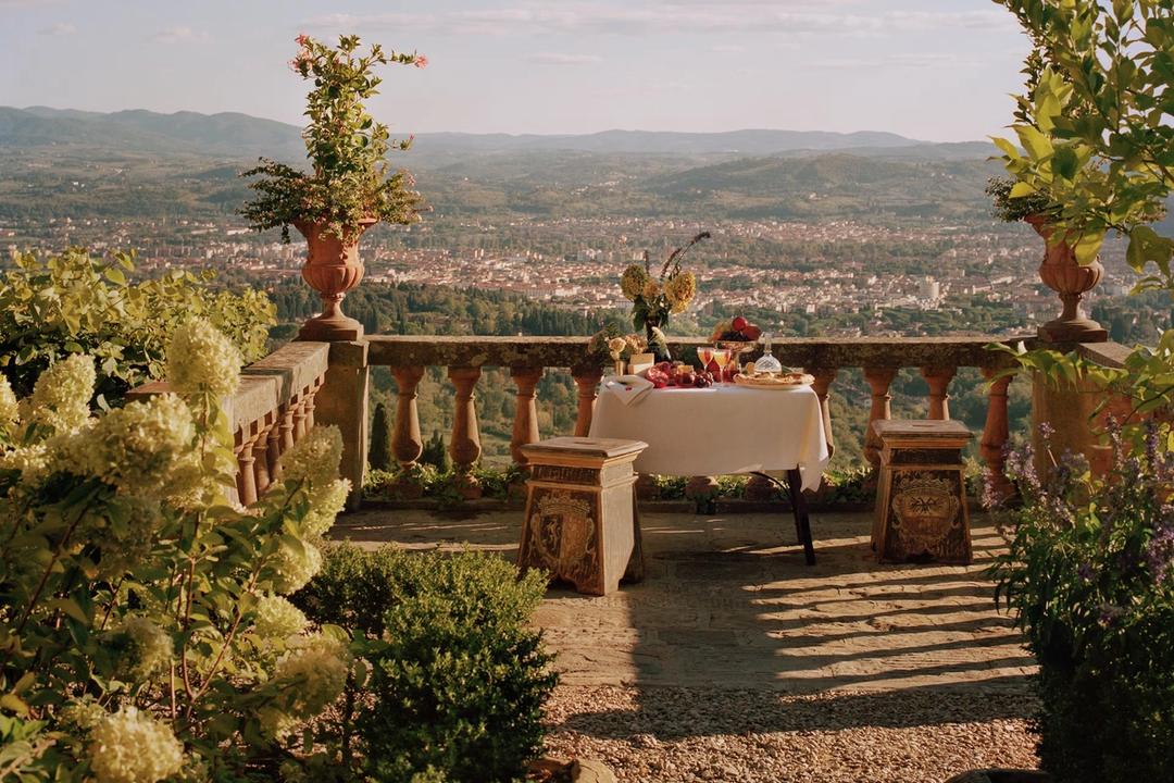 A table laid for lunch on a balustraded terrace, with Florence spread across the valley behind it