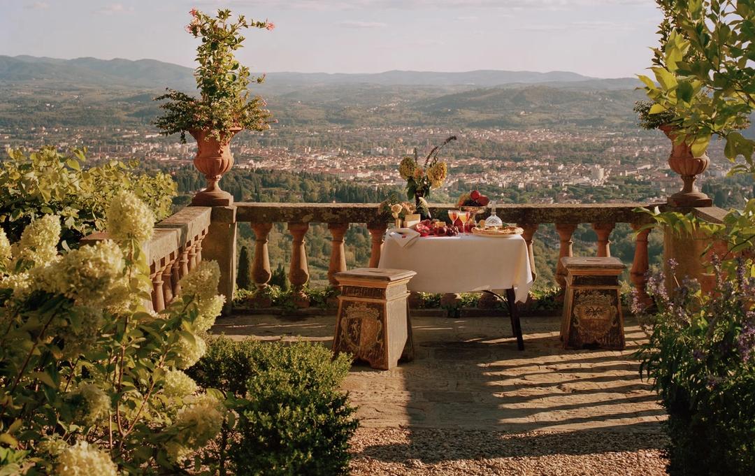 A table laid for lunch on a balustraded terrace, with Florence spread across the valley behind it
