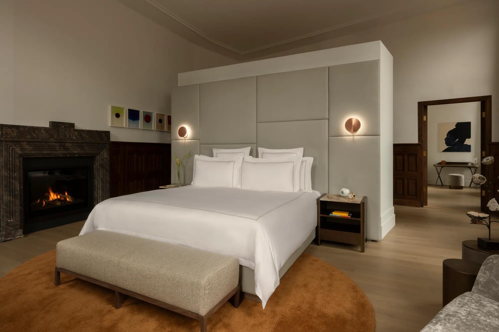 Rosewood Amsterdam: the Huis 020 bedroom with a white bed, a fireplace, and an orange rug