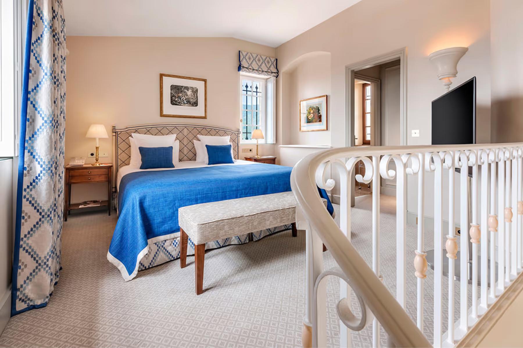Château Saint Martin & Spa: suite bedroom with blue bedding, fireplace, and child’s crib