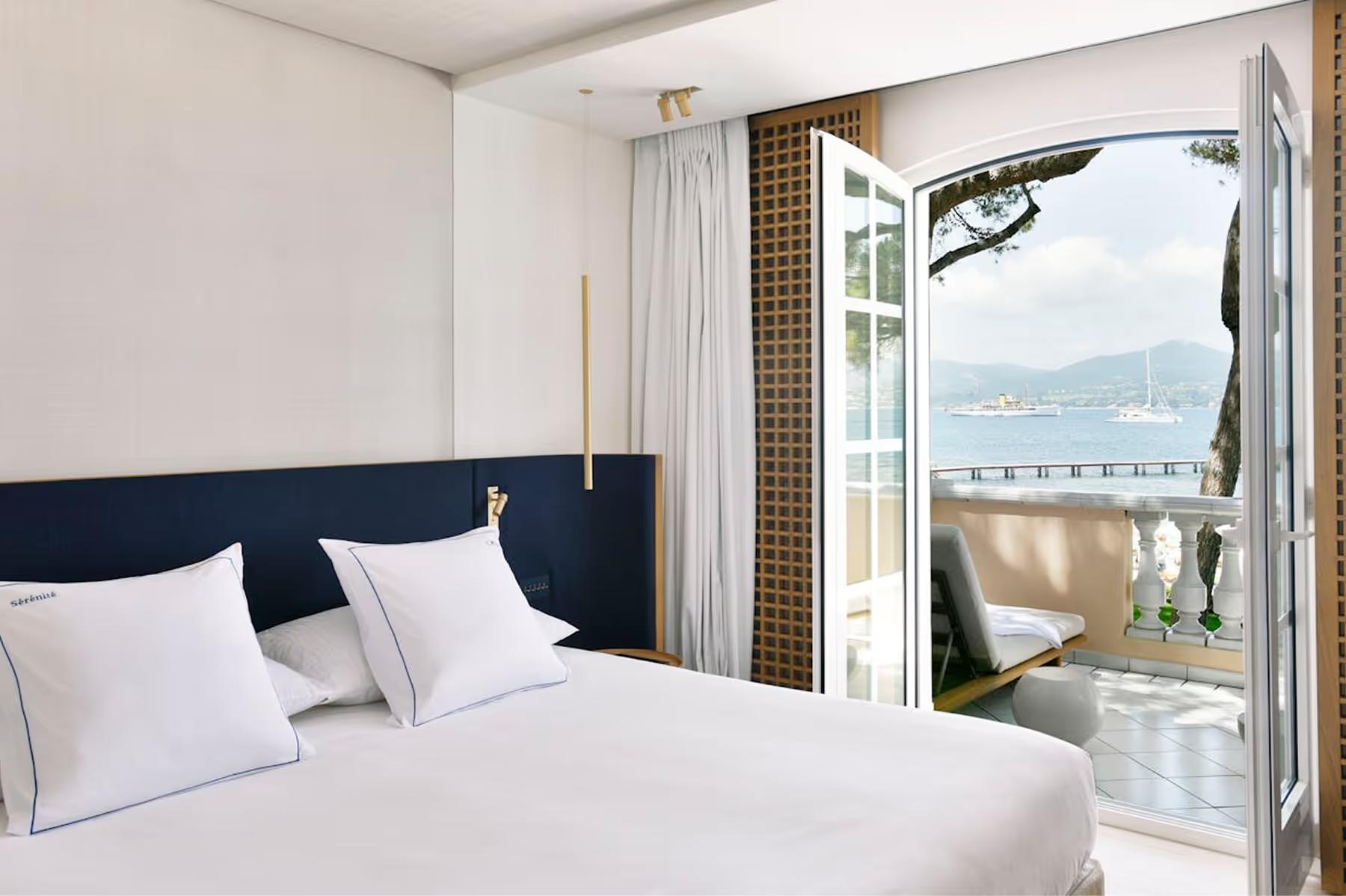 Bedroom with dark headboard, white linens, and sea access door