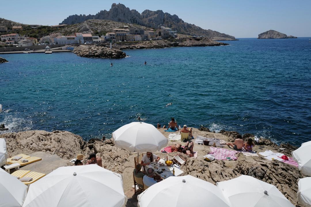 Swimmers and white parasols on the rocks above the sea in Marseille