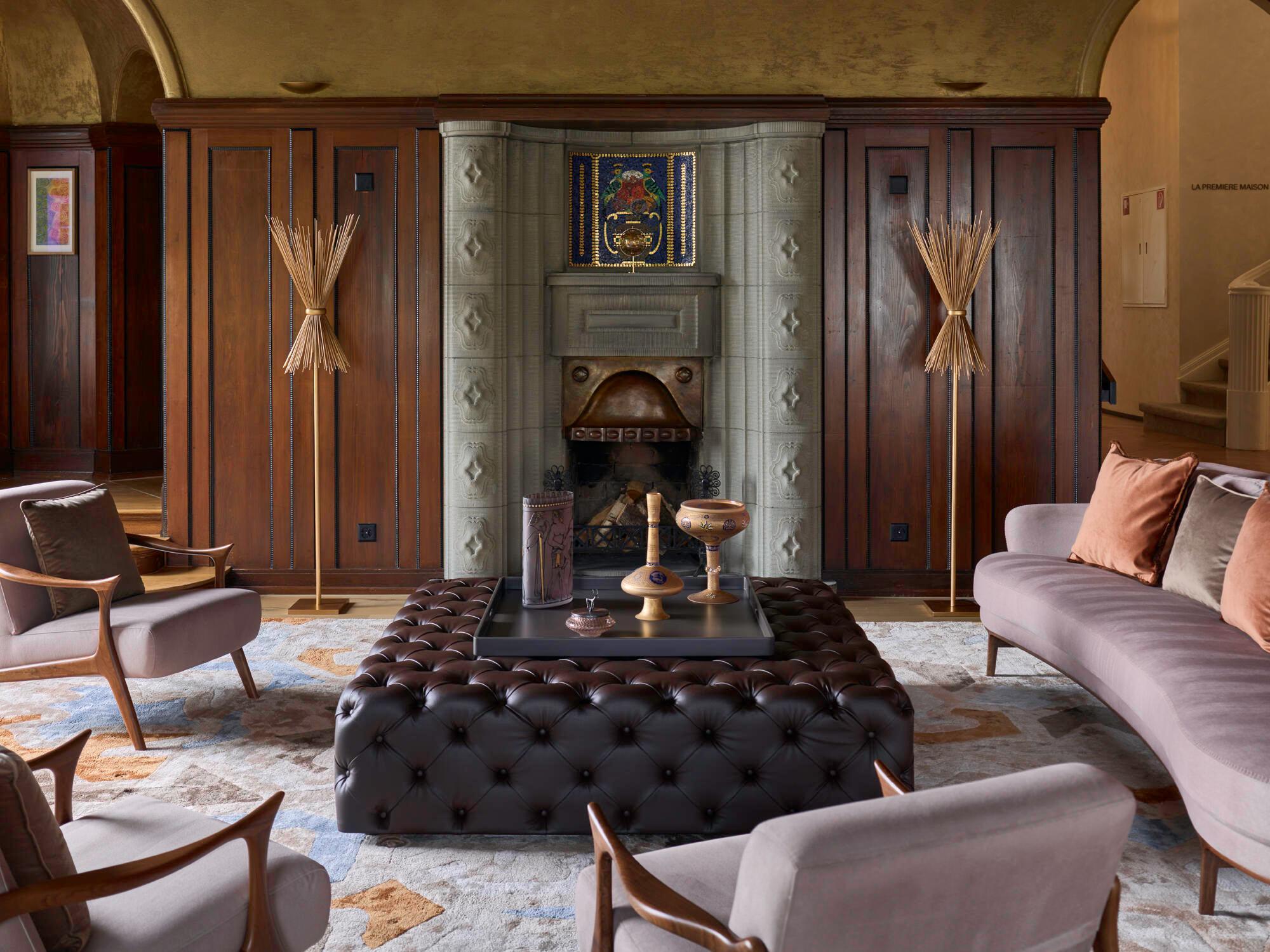 Richly furnished lounge with burgundy wood paneling, fireplace, and tufted seating