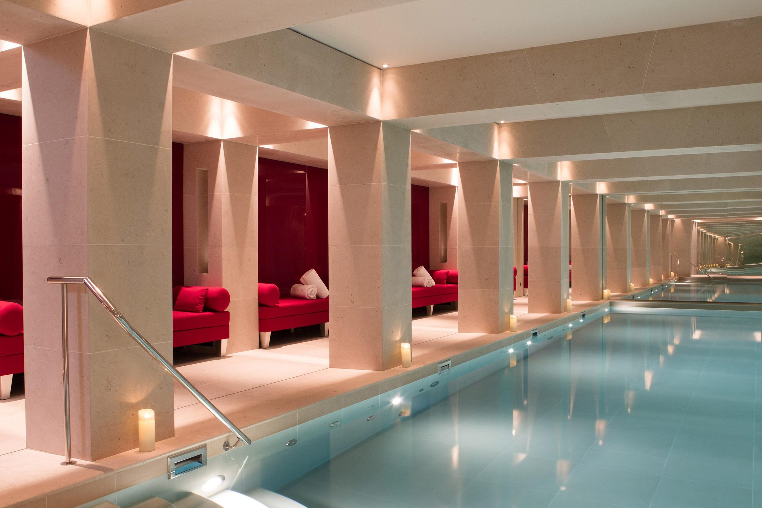 La Réserve Paris: an indoor pool with red velvet seating alcoves and symmetrical warm lighting
