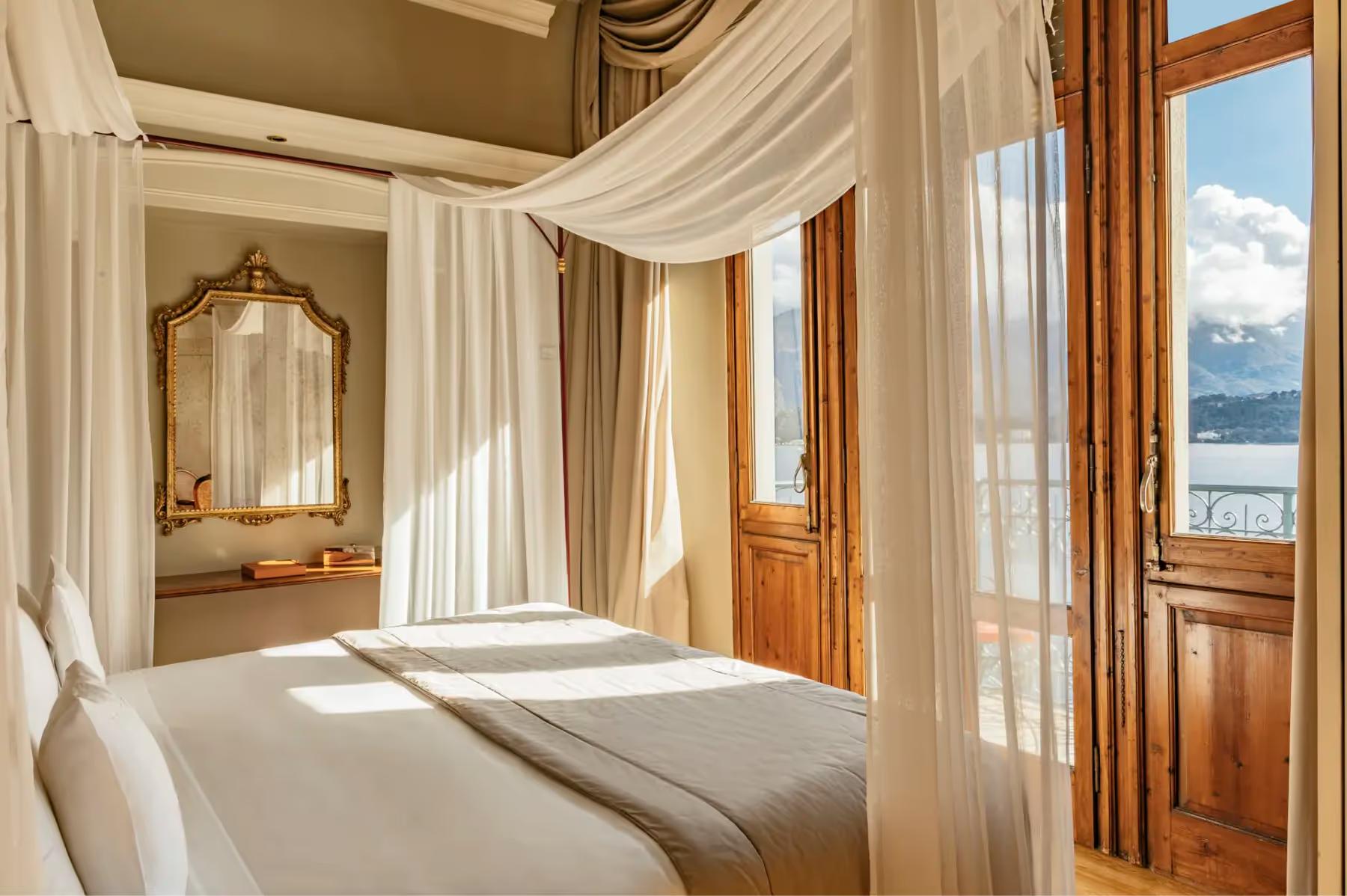 Grand Hotel Tremezzo: a suite bedroom with draped canopy bed, marble vanities, and mountain lake views