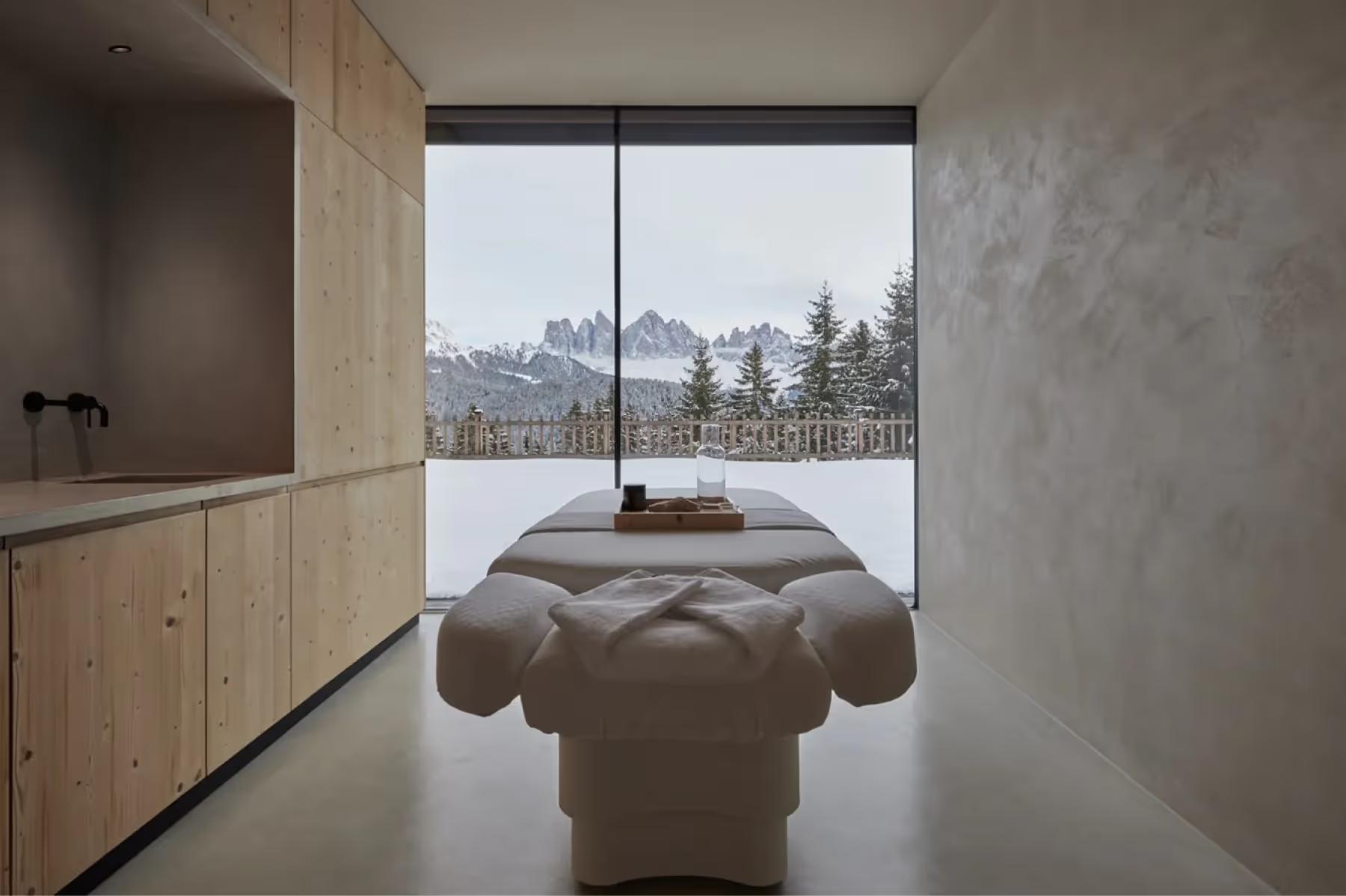 Forestis: a meditation spa room with a sculptural cushioned bench centered by a window overlooking mountains