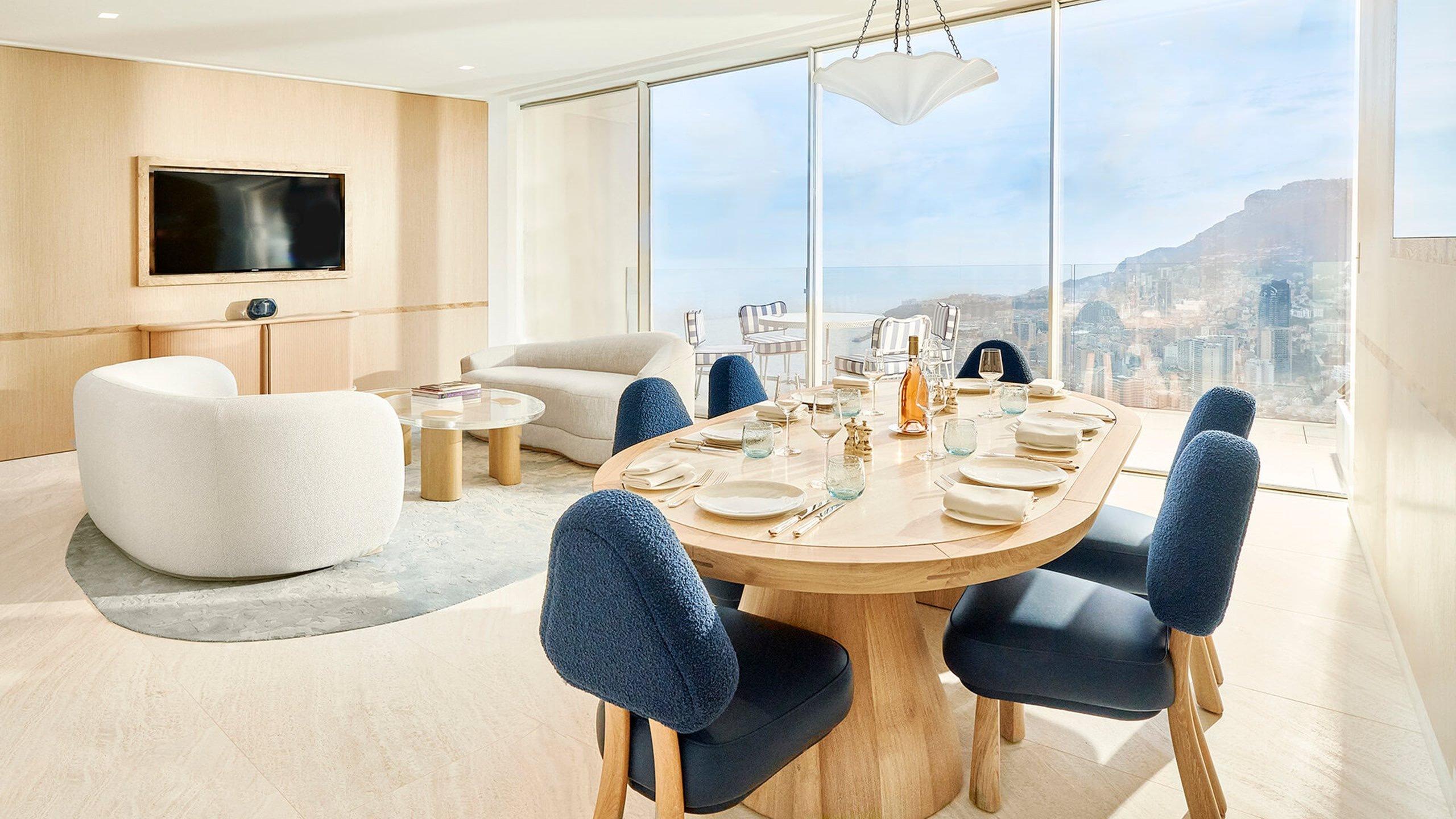 Suite with white cylindrical tub and dining area overlooking coastal landscape