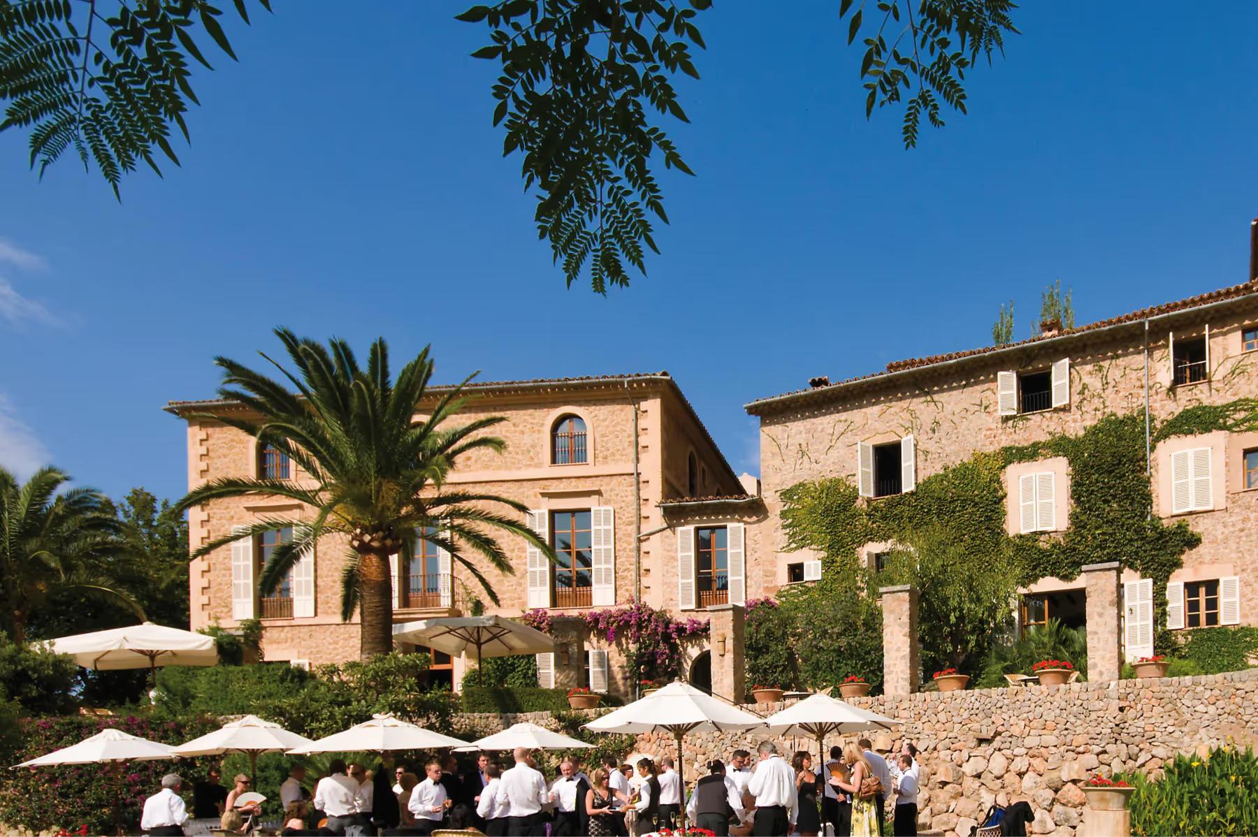 La Residencia: stone manor buildings with palm tree, outdoor seating area, and Mediterranean landscape