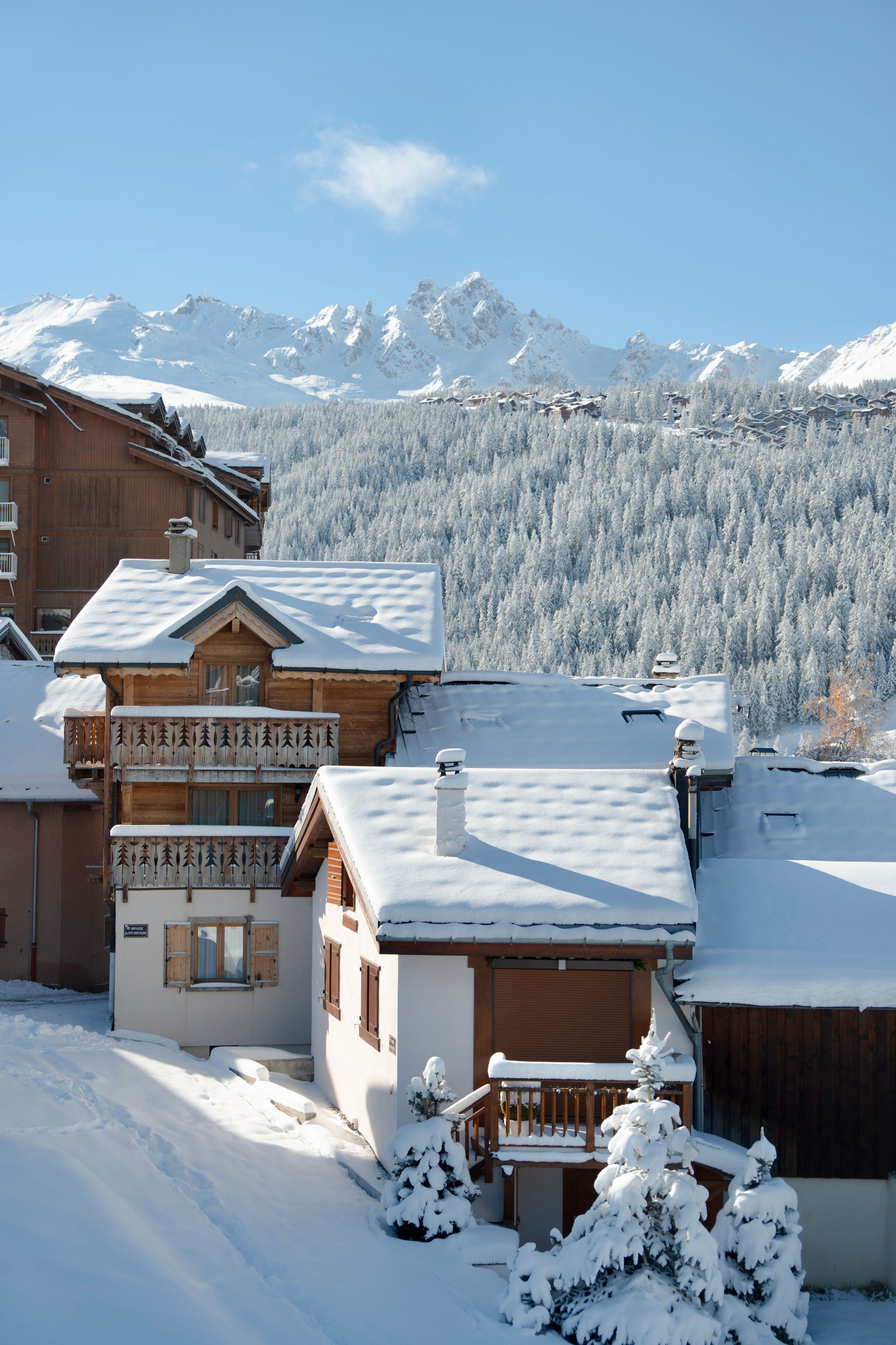 Snow-covered chalets in Courchevel with forested peaks behind