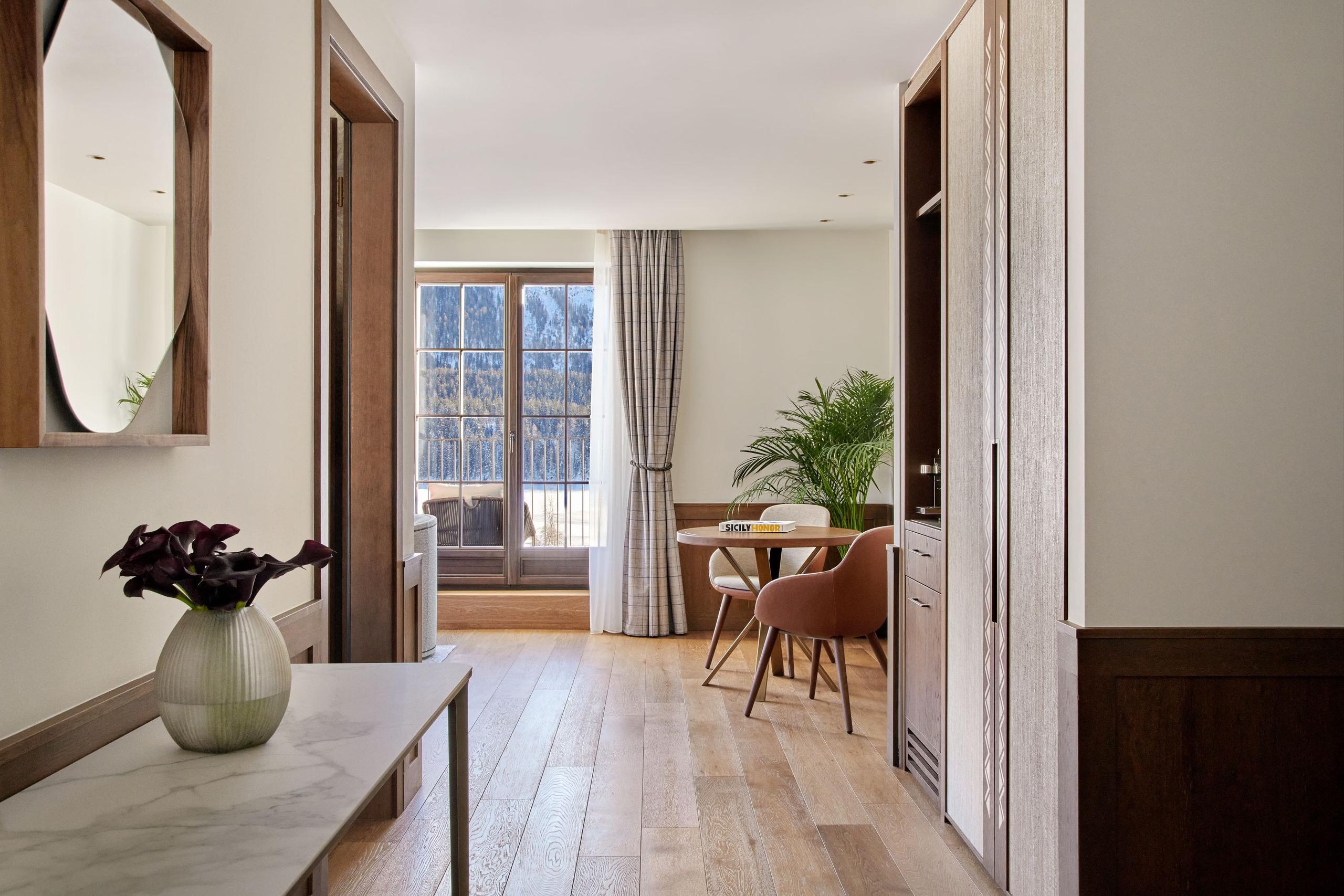 Hallway with white walls, mirror, wood details, and mountain views through open doors