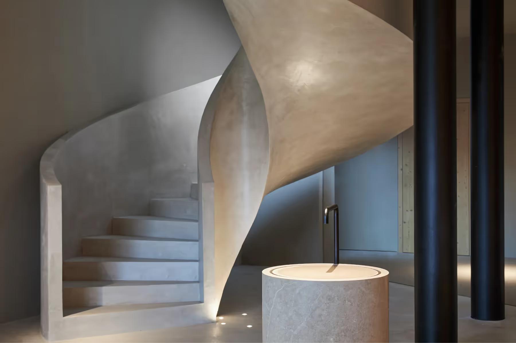 Forestis: a sculptural spiral staircase with concrete and wood framing in the spa wellness area