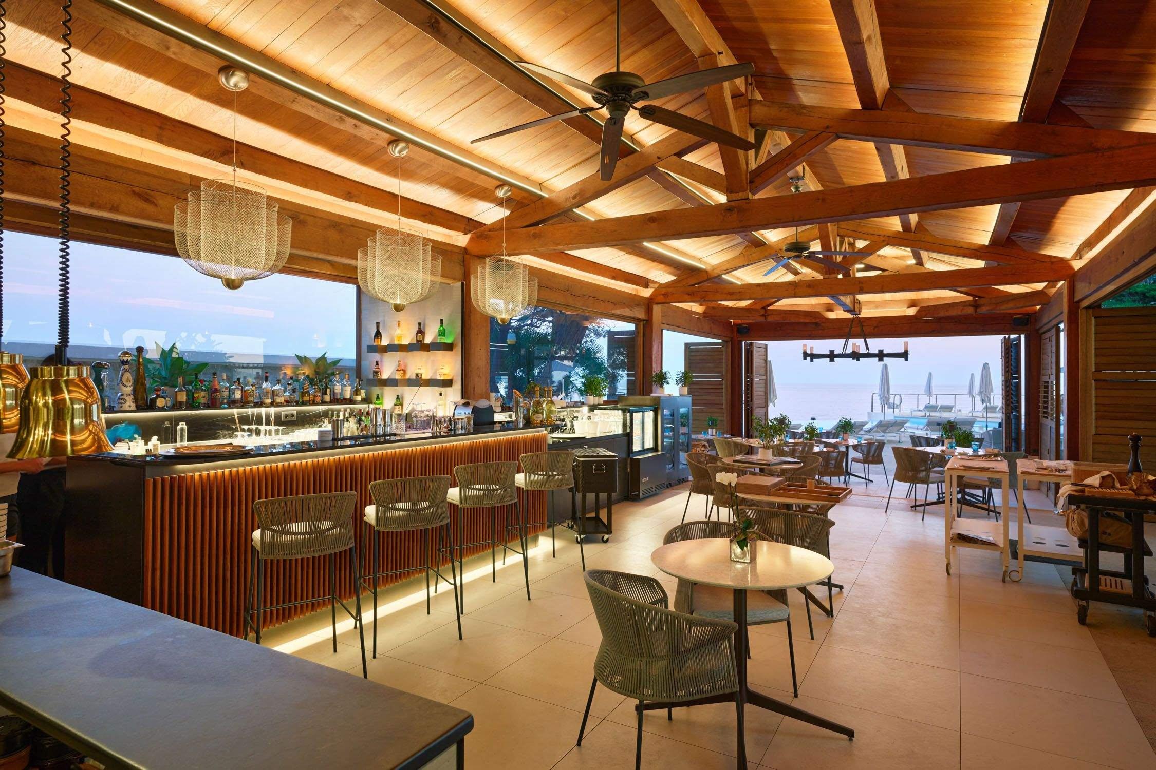 A bar area with wooden slat surfaces and views to the sea