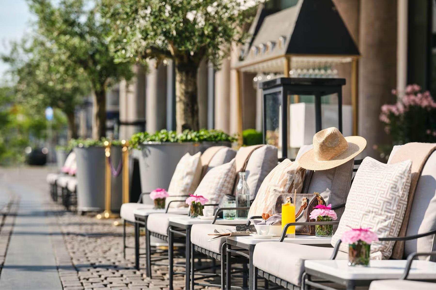 Hotel d’Angleterre: sidewalk seating area with cushioned chairs and flowering planters