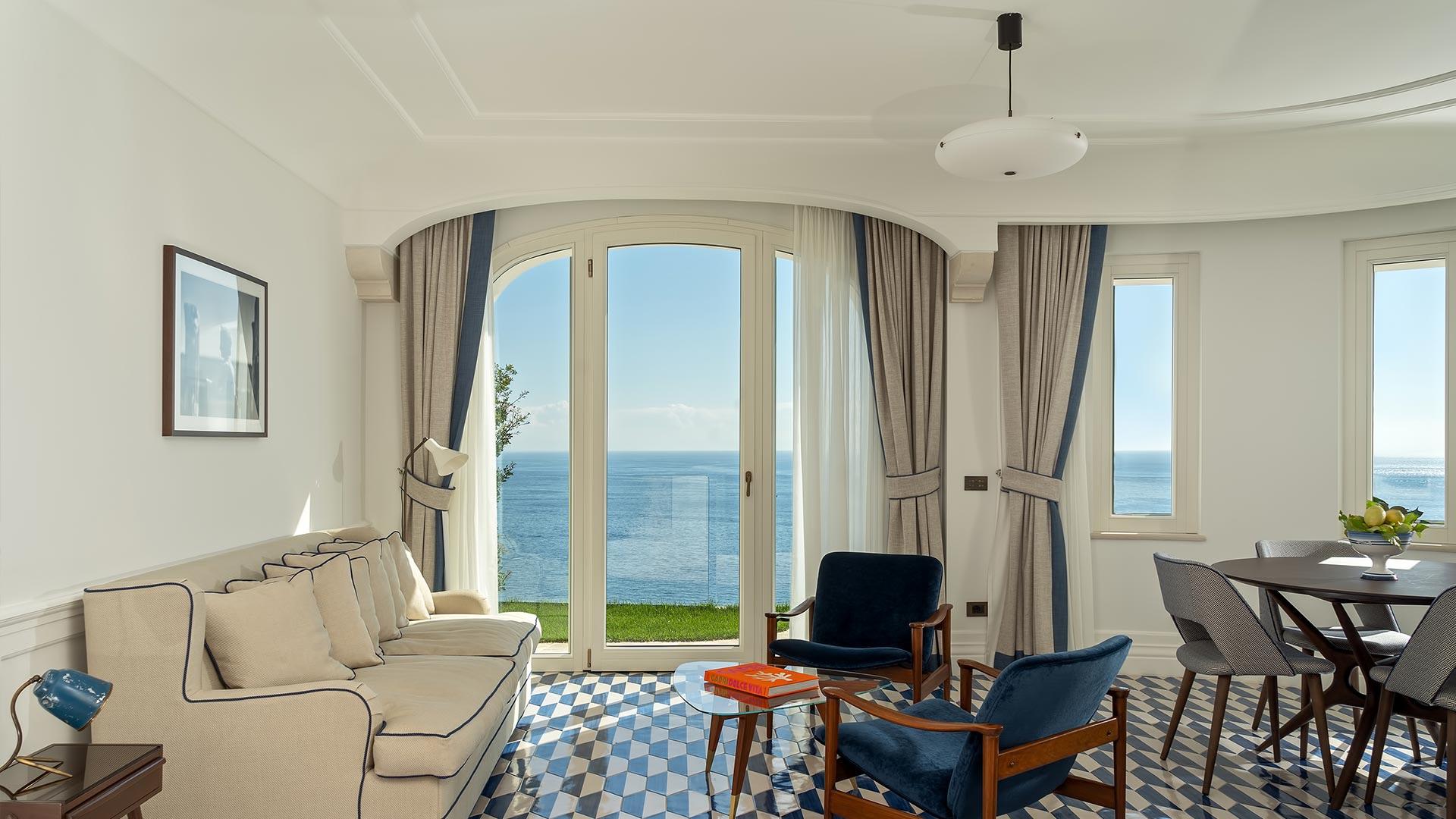 Light-filled room with patterned flooring, arched windows framing sea vista, and seating area