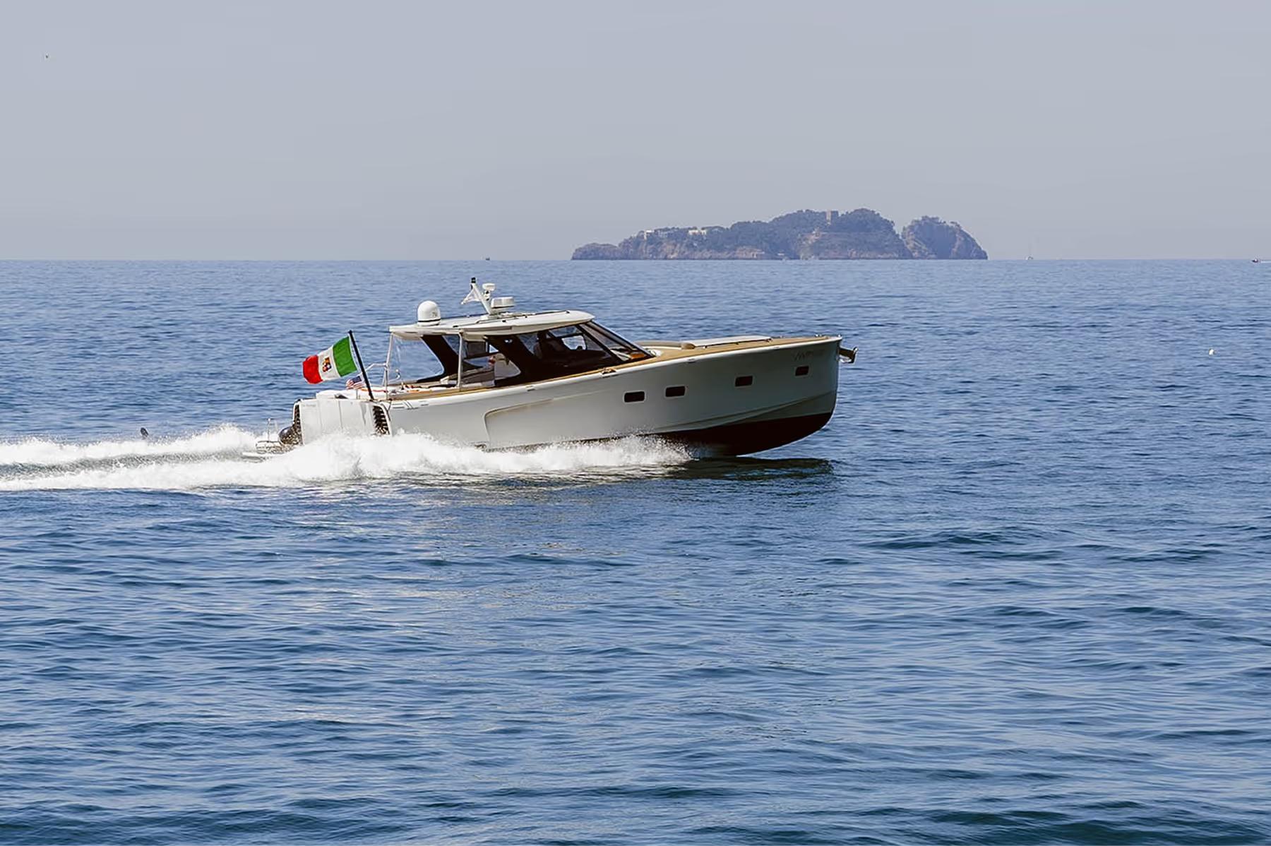 Motorboat on blue water heading toward distant cliffs and islands under clear sky