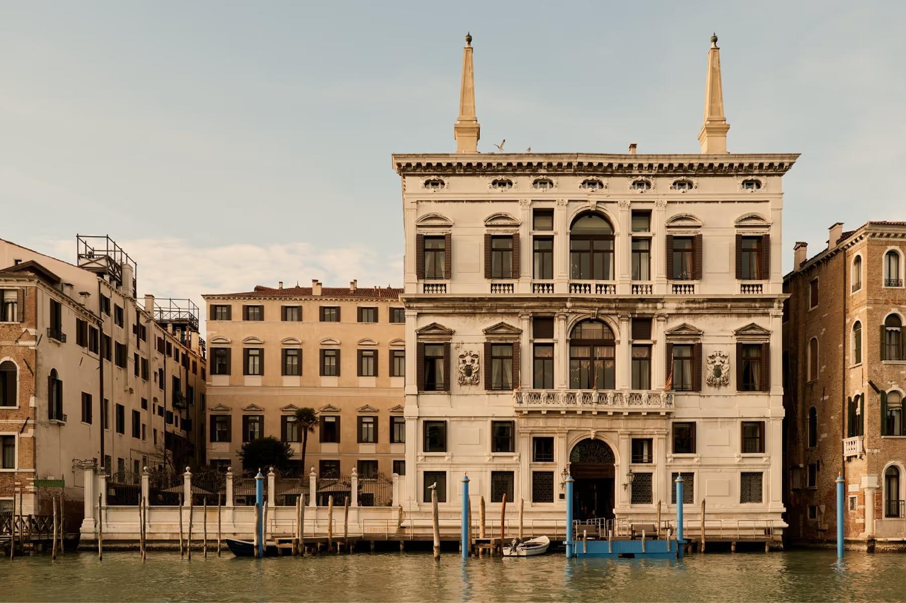 A cream-colored Baroque palazzo facade on the Grand Canal with classical columns and symmetrical windows