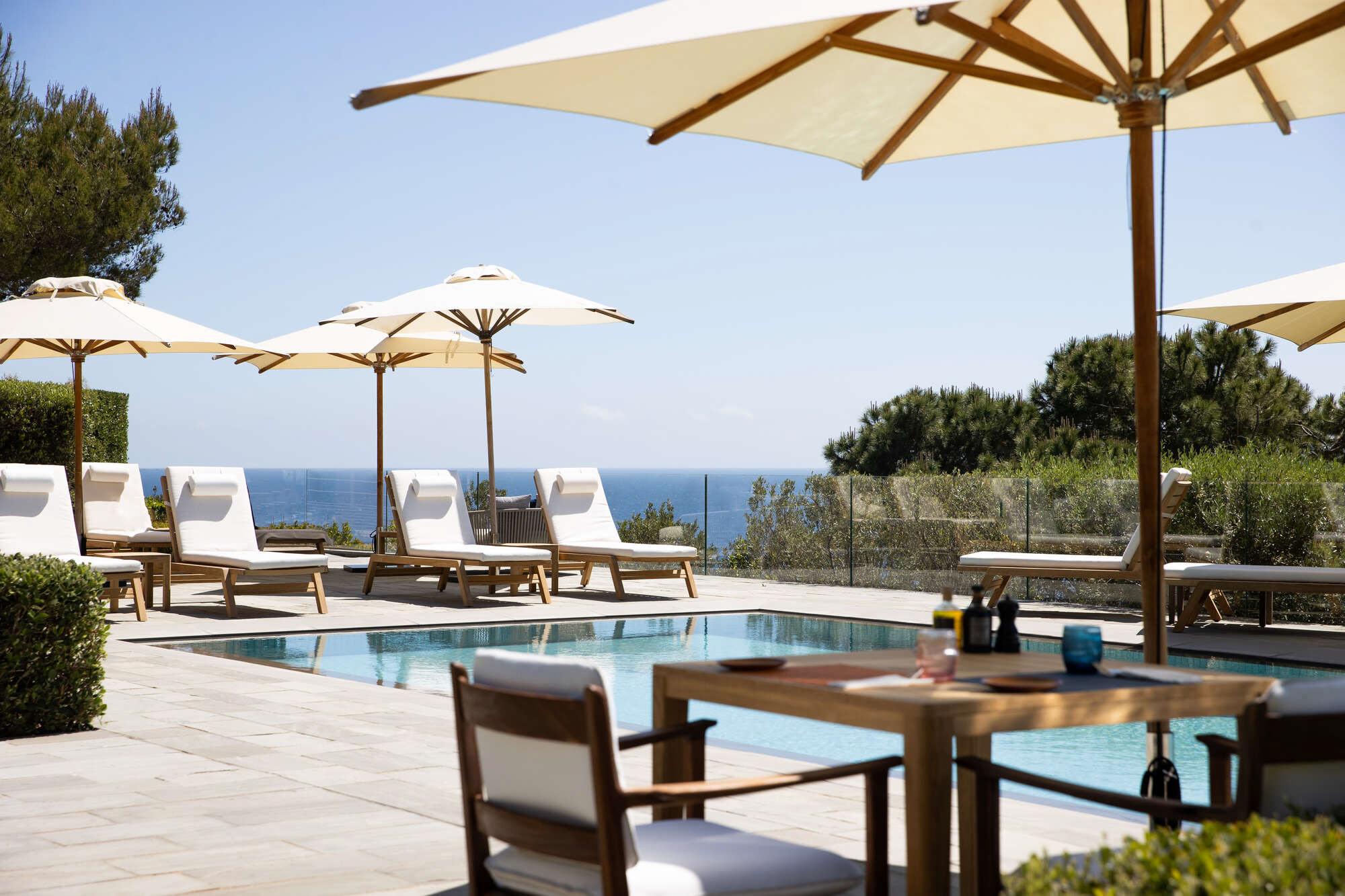 La Réserve Ramatuelle: pool with white lounges and tables beneath wooden umbrellas
